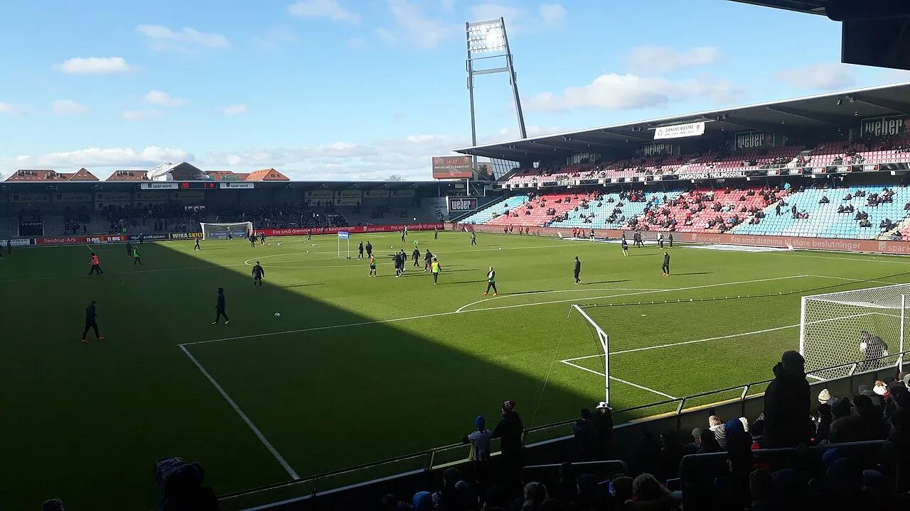 A football team prepares for a match under stadium lights.
