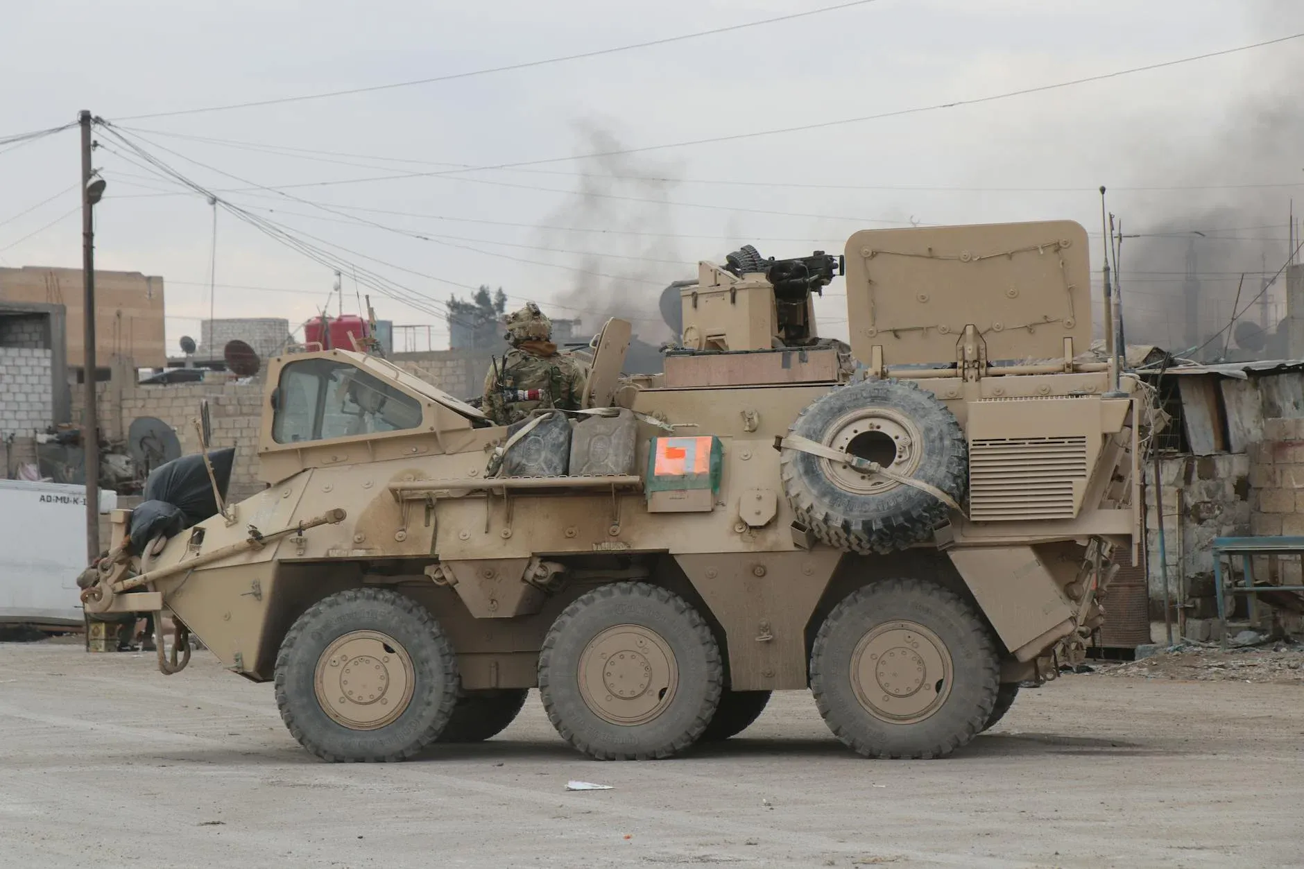A military vehicle navigating through an urban conflict environment in Al Hasakah, Syria, highlighting the tense atmosphere of the region.