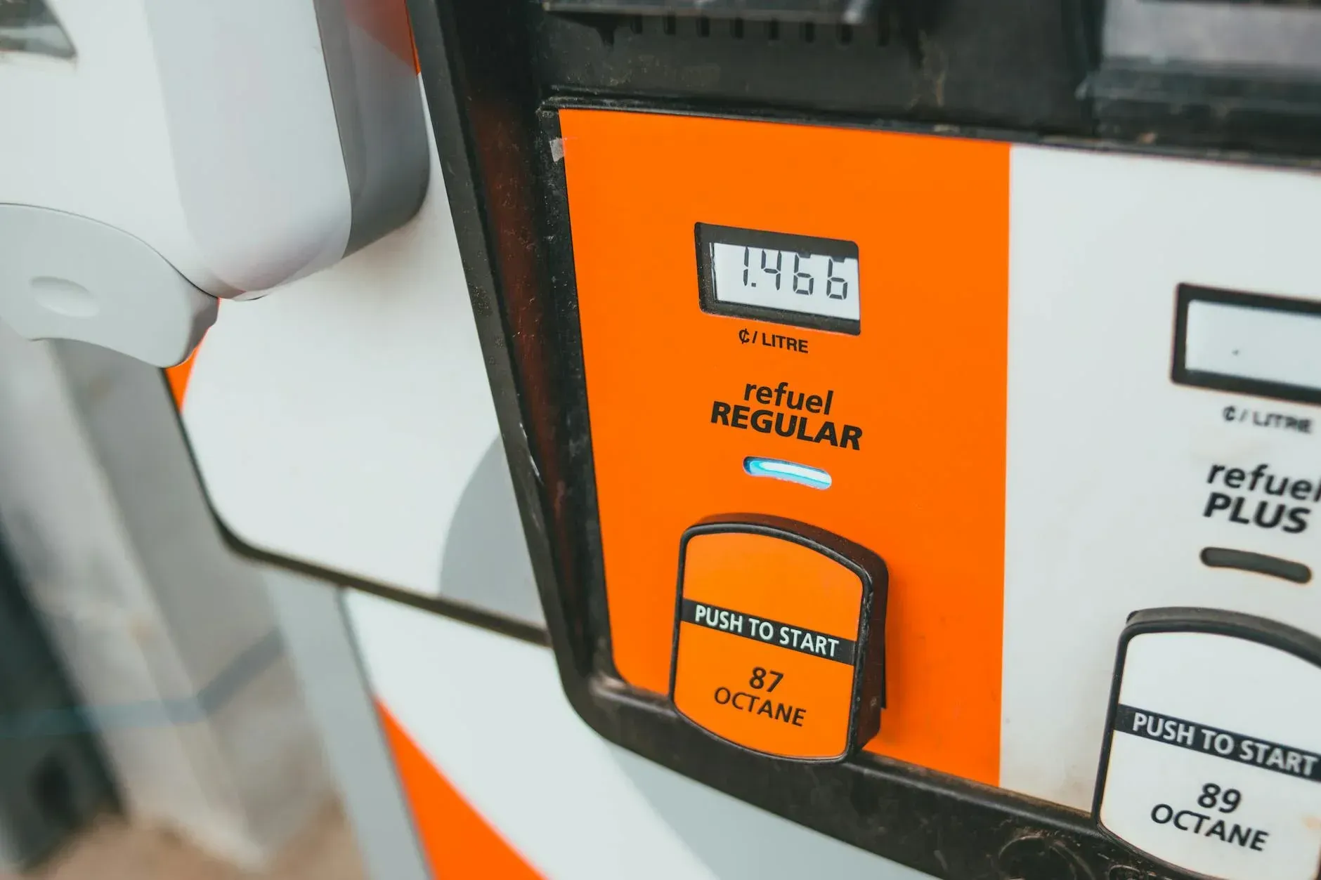 Nærbillede af en benzinstationsstander, hvor pris og oktantal (87) fremgår tydeligt. Billedet illustrerer hverdagsnære energipriser og brændstofspecifikationer.