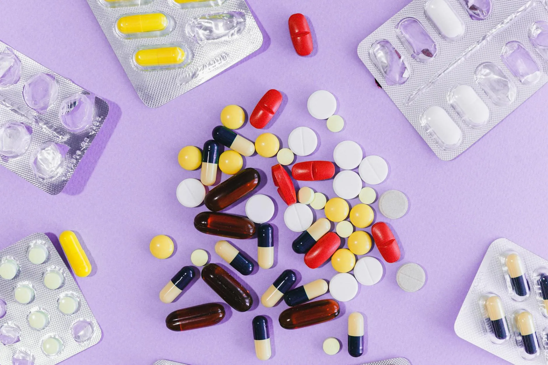 A vibrant display of colorful pills and capsules in blister packs on a purple background.