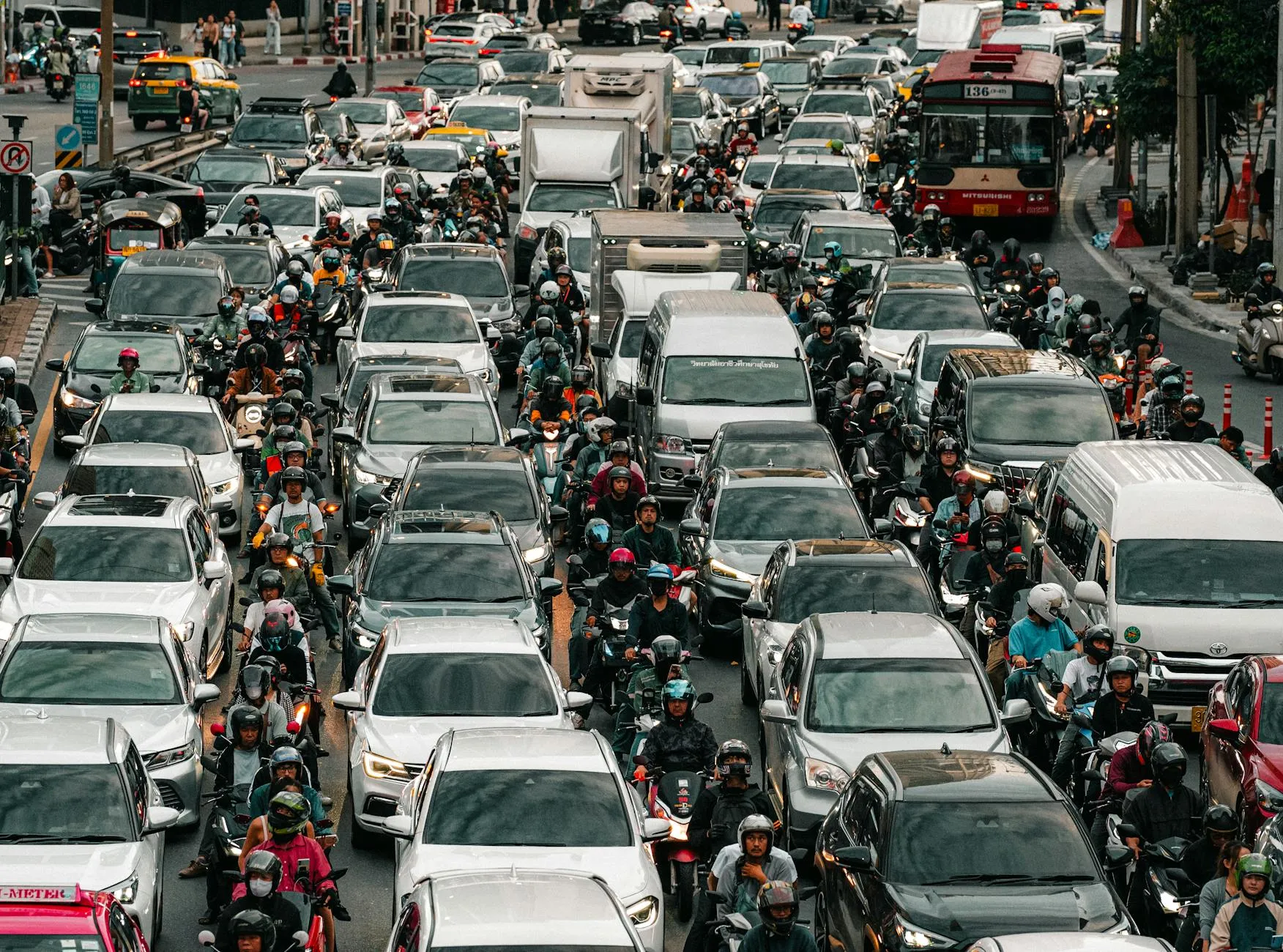 Aerial view of heavy traffic congestion on a bustling city street with cars, motorcycles, and pedestrians.
