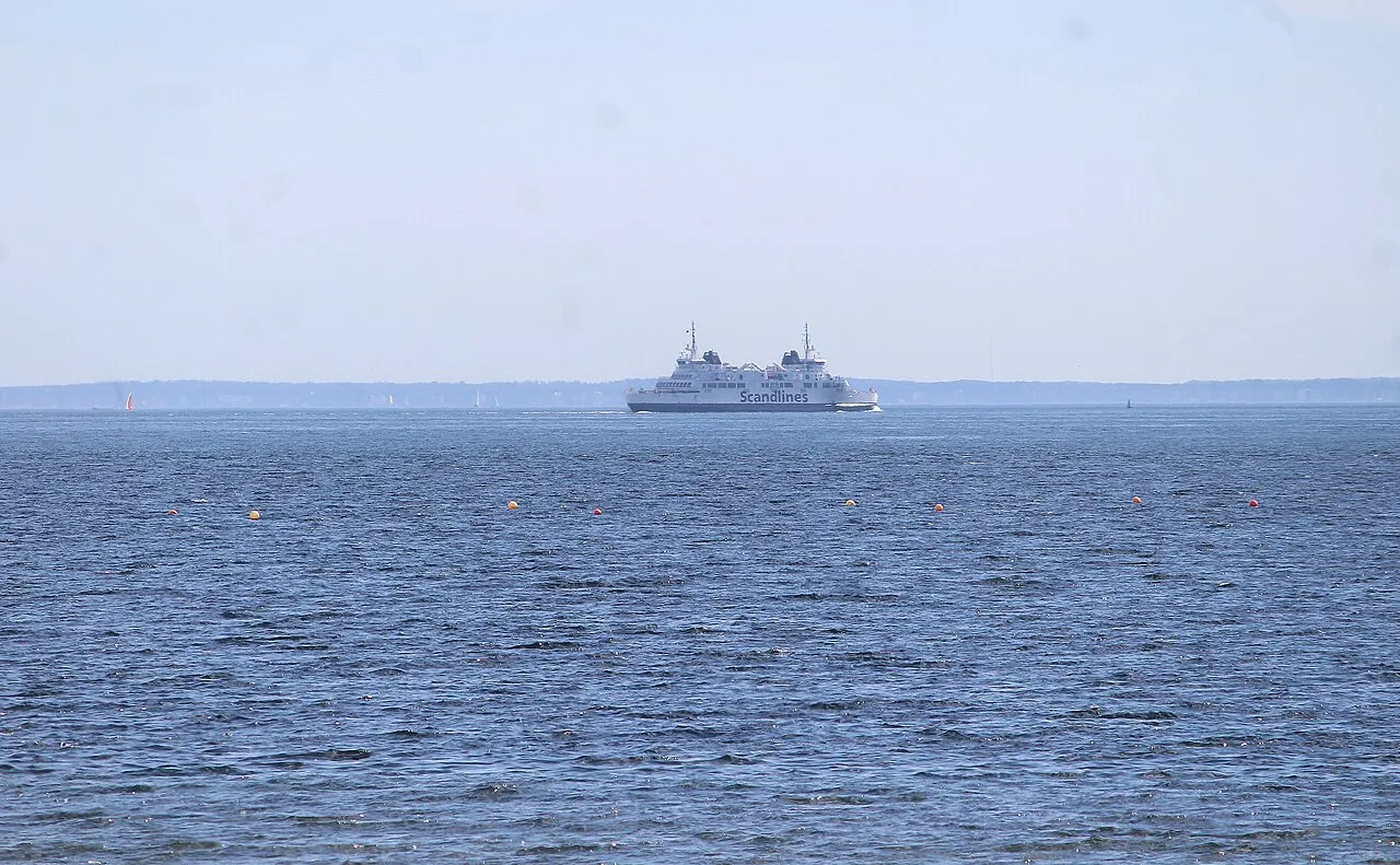 En færge sejler på Øresund med Sofiero i Helsingborg i baggrunden. Billedet fanger forbindelsen mellem landene over sundet.