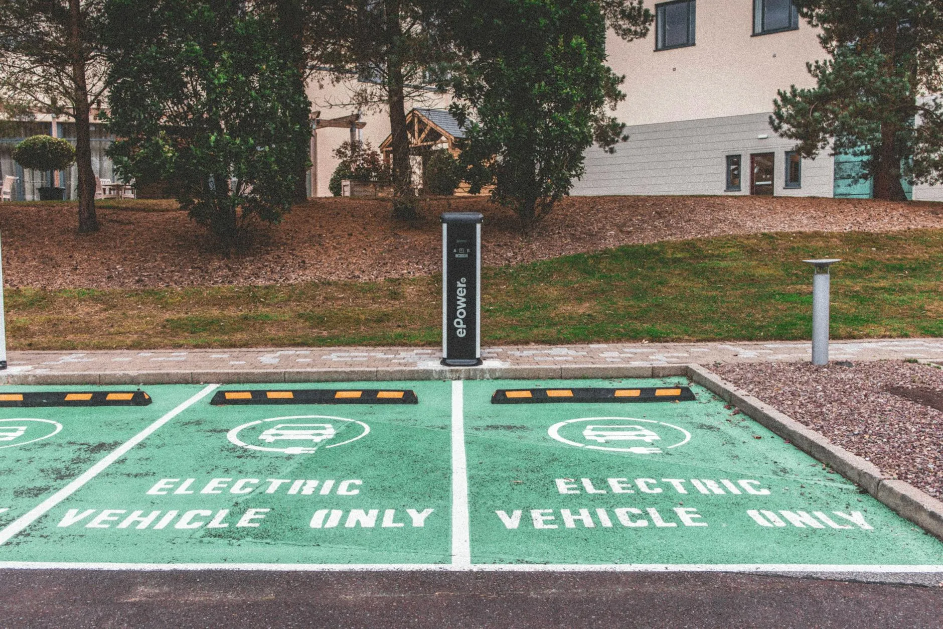 En grøn elbilparkering med ladestation i et urbant miljø. Billedet viser elbiler i en moderne infrastruktur-kontekst.