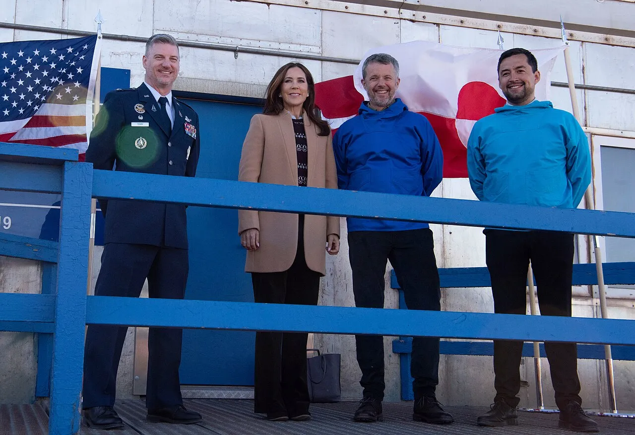 Kong Frederik X og Dronning Mary smiler sammen med bl.a. U.S. Space Force-kol. Jason Terry og Grønlands premierminister Múte Bourup Egede ved Pituffik Space Base. Besøget fandt sted i forbindelse med turen til Qaanaaq i juni 2024.