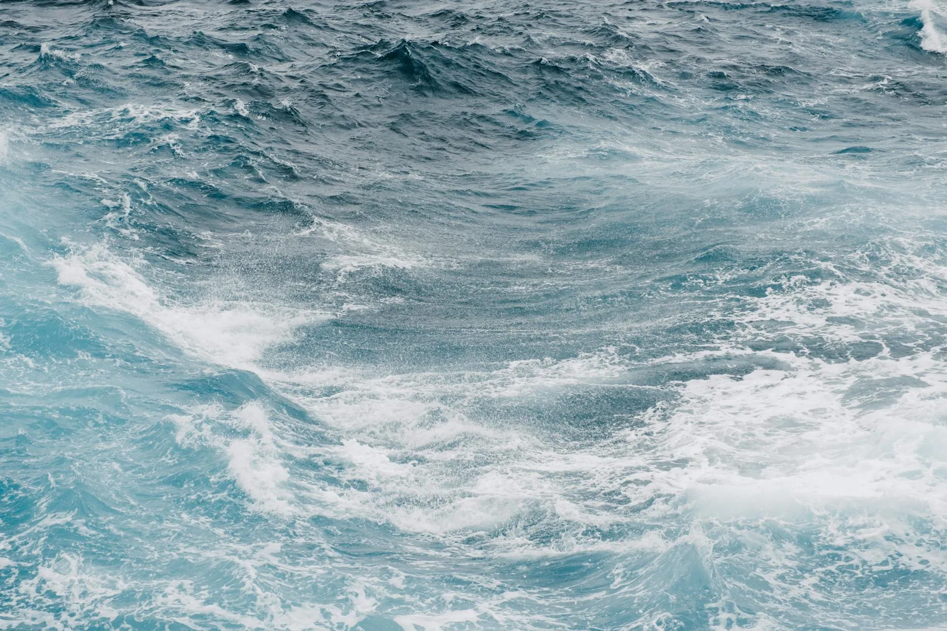 Vibrerende og kraftfulde havbølger bryder og hvirvler i havet. Naturens energi og bevægelse står tydeligt frem i billedet.