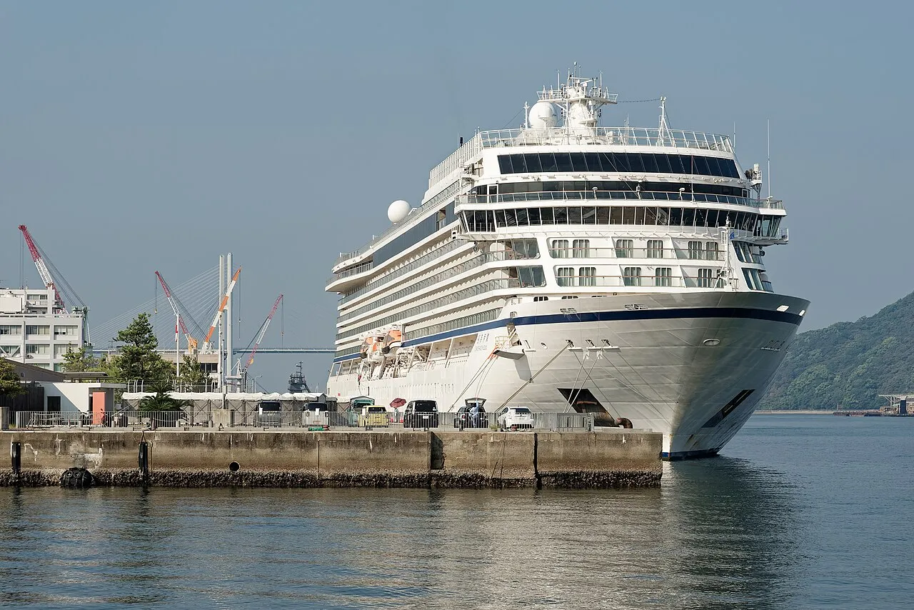 Et krydstogtskib ligger ved kaj i havnen i Nagasaki. Billedet fanger skibet i havnemiljøet med tydelig kontekst fra kajområdet.