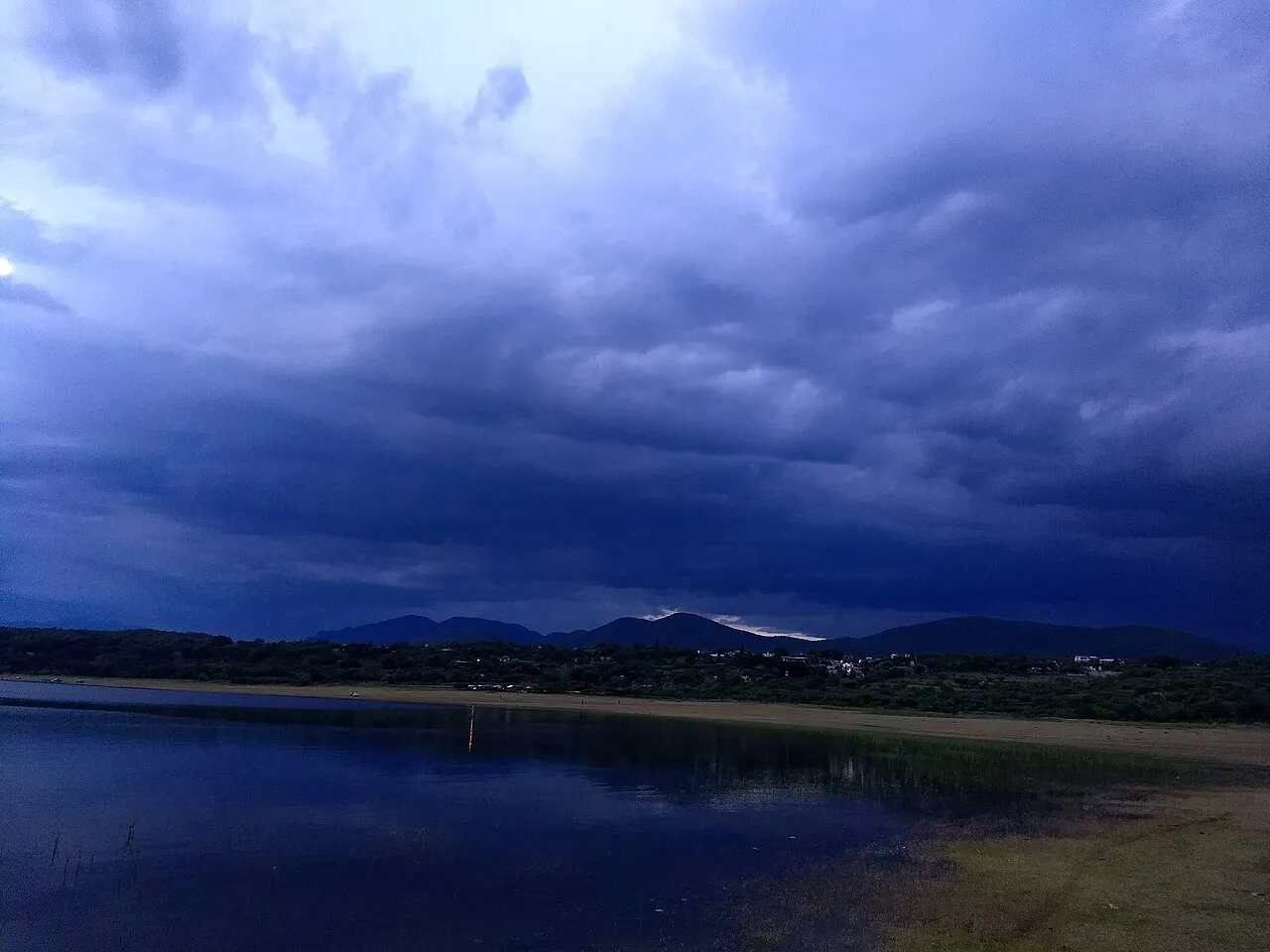 Fotografi af lagunen El Rodeo ved solnedgang i Miacatlán. Stemningen er præget af det varme aftenlys over vandet.