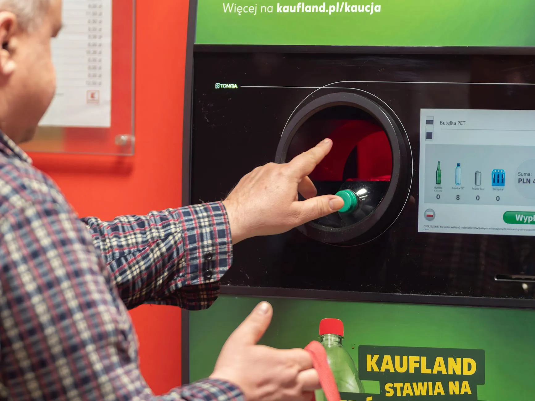 En mand indsætter en plastflaske i en returmaskine i Kaufland i Wrocław, Polen. Situationen illustrerer genbrug og pantordninger i praksis.