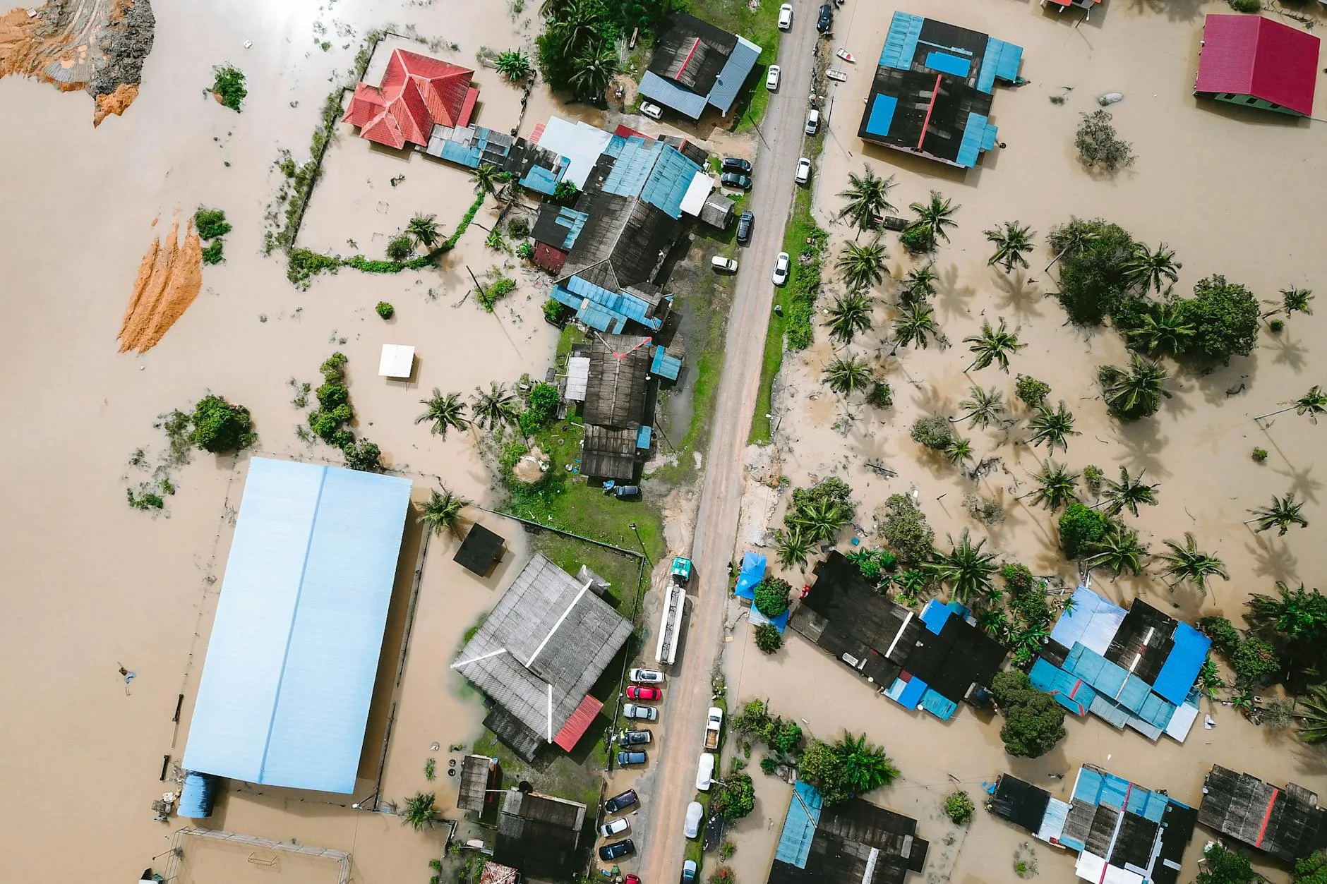 Et dronefoto viser omfattende oversvømmelser i Kijal, Malaysia, hvor bygninger står under vand. Området fremstår stærkt påvirket af vandmasserne.