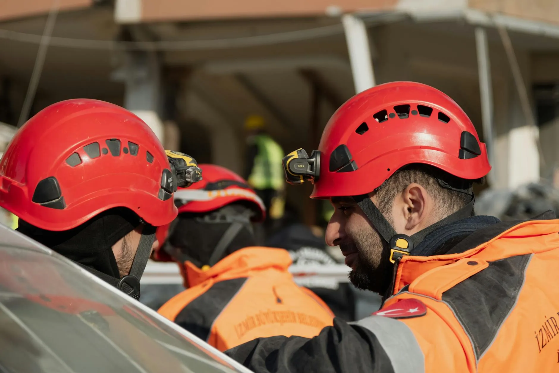 Emergency responders i hjelme samarbejder under en redningsaktion i Antakya, Türkiye. Billedet viser fokus og teamwork i en akut situation.