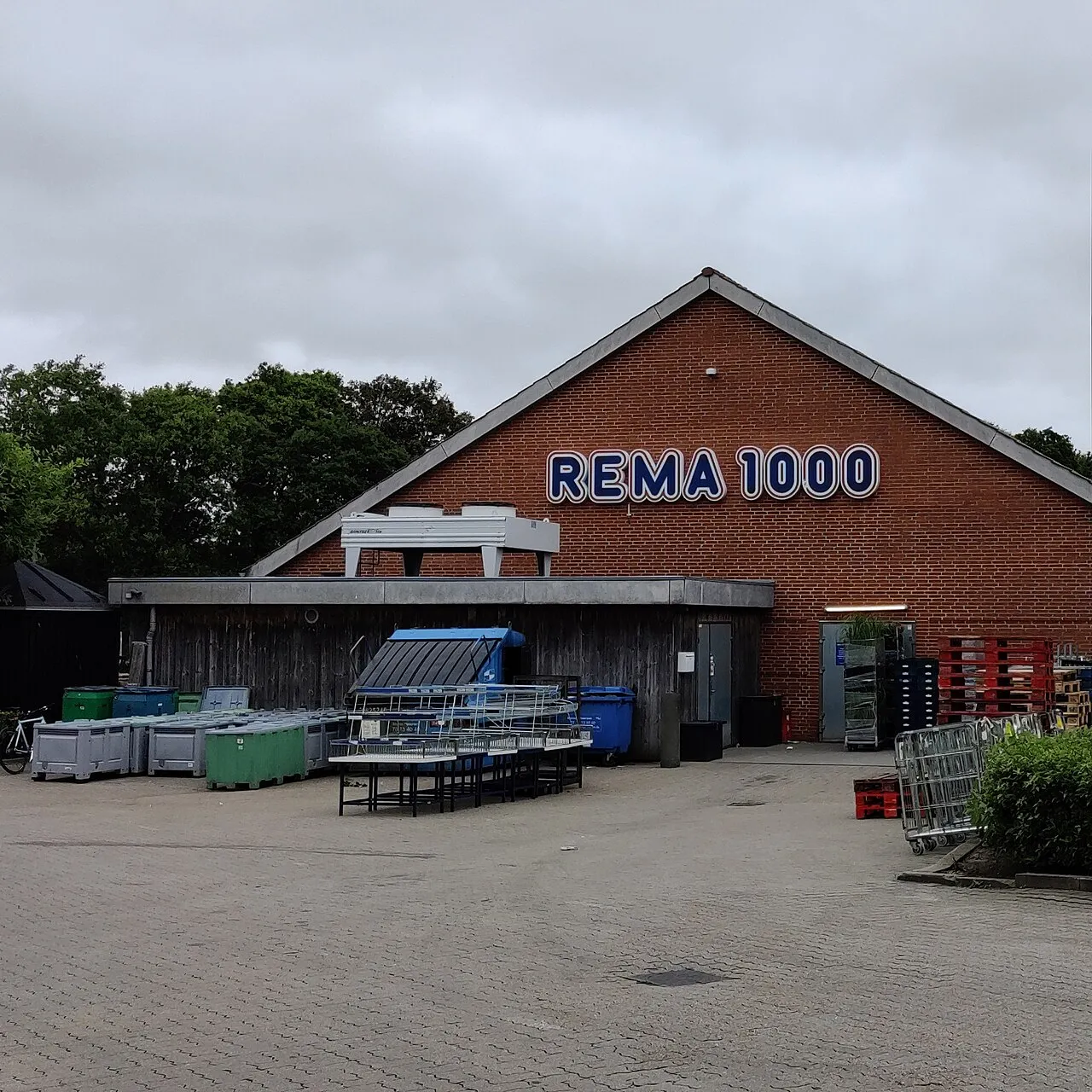 Et beskåret udsnit af facaden på en REMA 1000-butik i Esbjerg. Billedet fremhæver butikkens moderne udtryk.