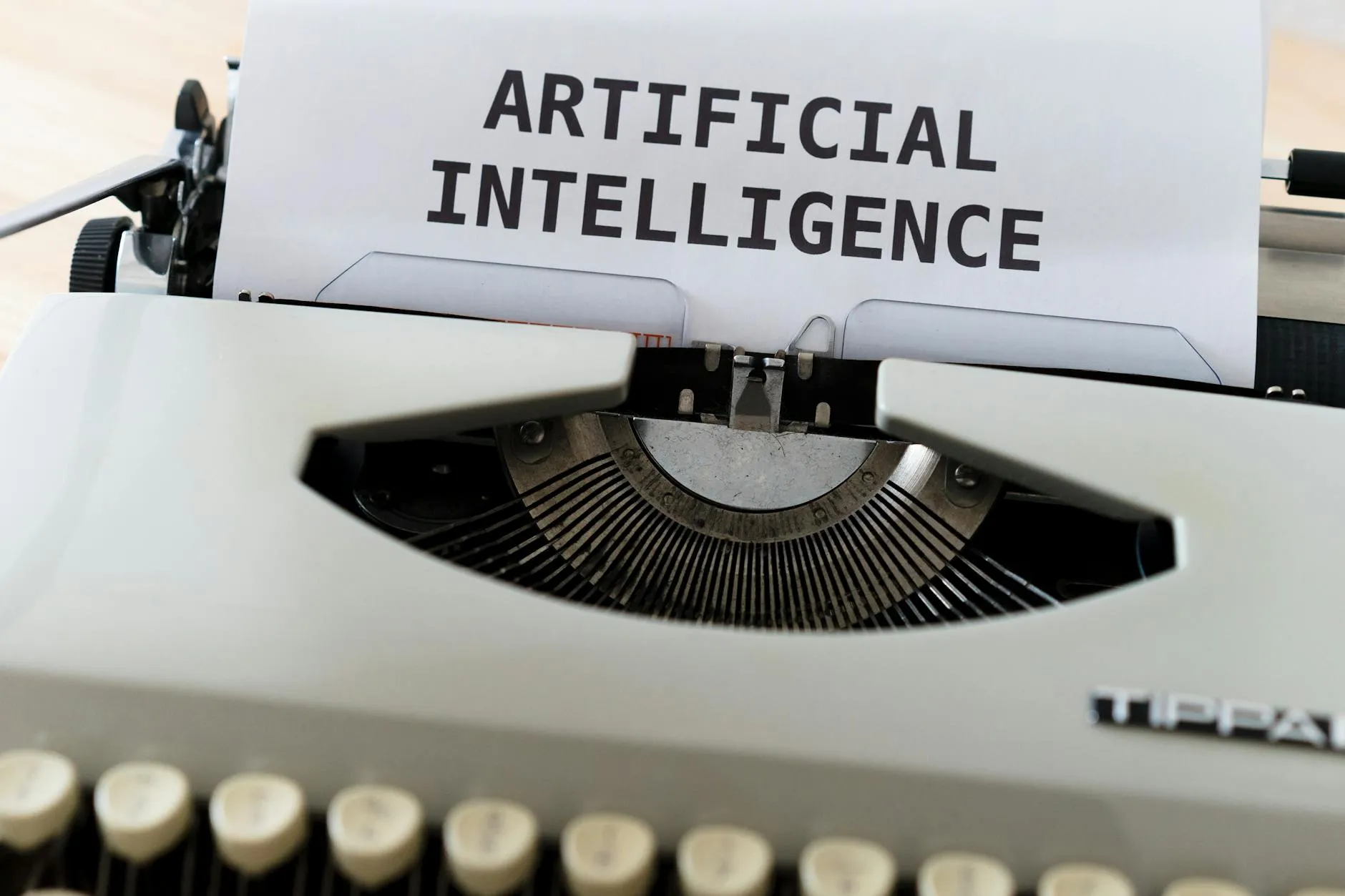 Et close-up af en skrivemaskine, hvor der står “ARTIFICIAL INTELLIGENCE” på papiret. Motivet understreger temaet kunstig intelligens og teknologi.