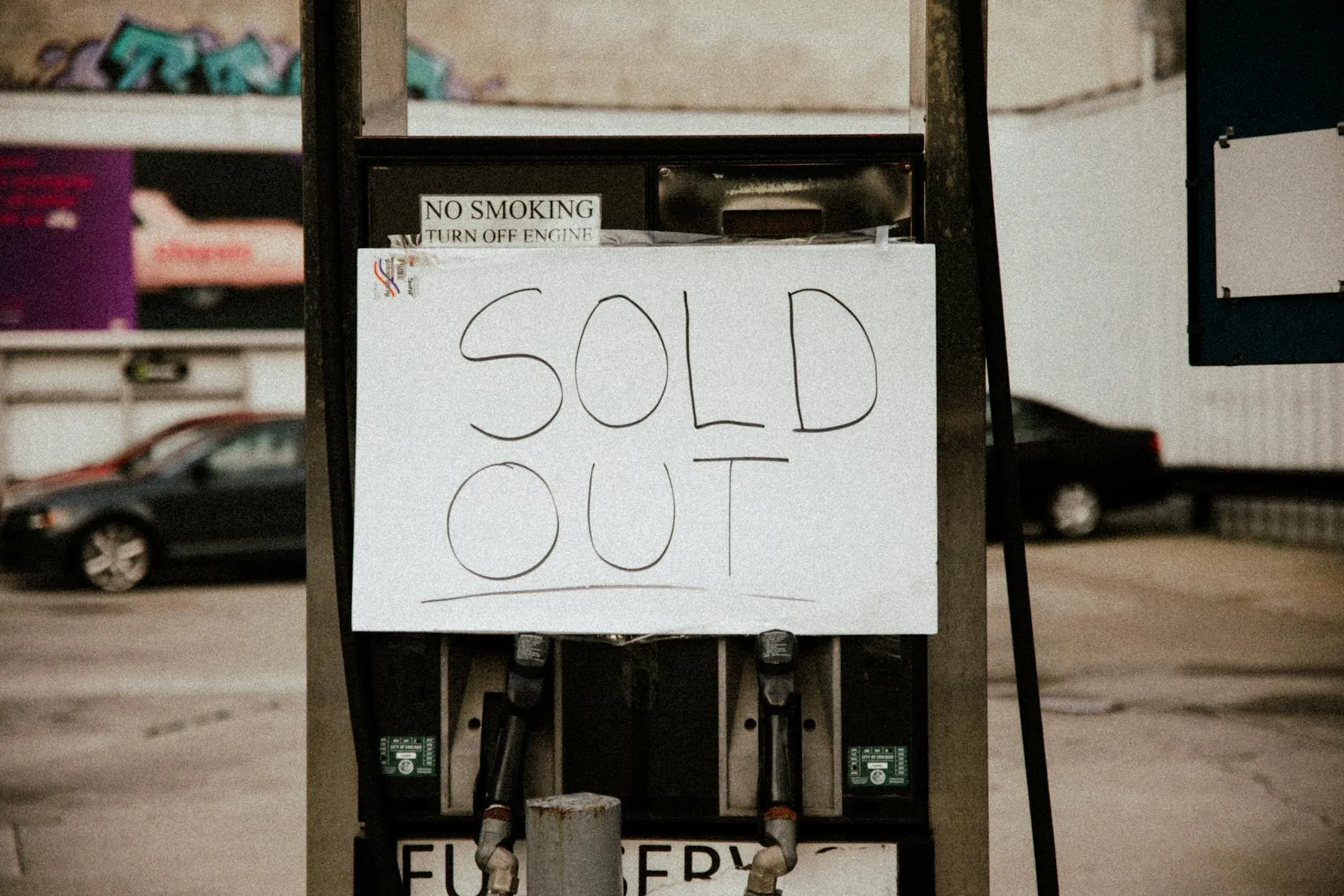 En tankstation viser et “Sold Out”-skilt på en benzinpumpe, som illustrerer brændstofmangel. Billedet formidler en akut forsyningsudfordring i bymiljøet.