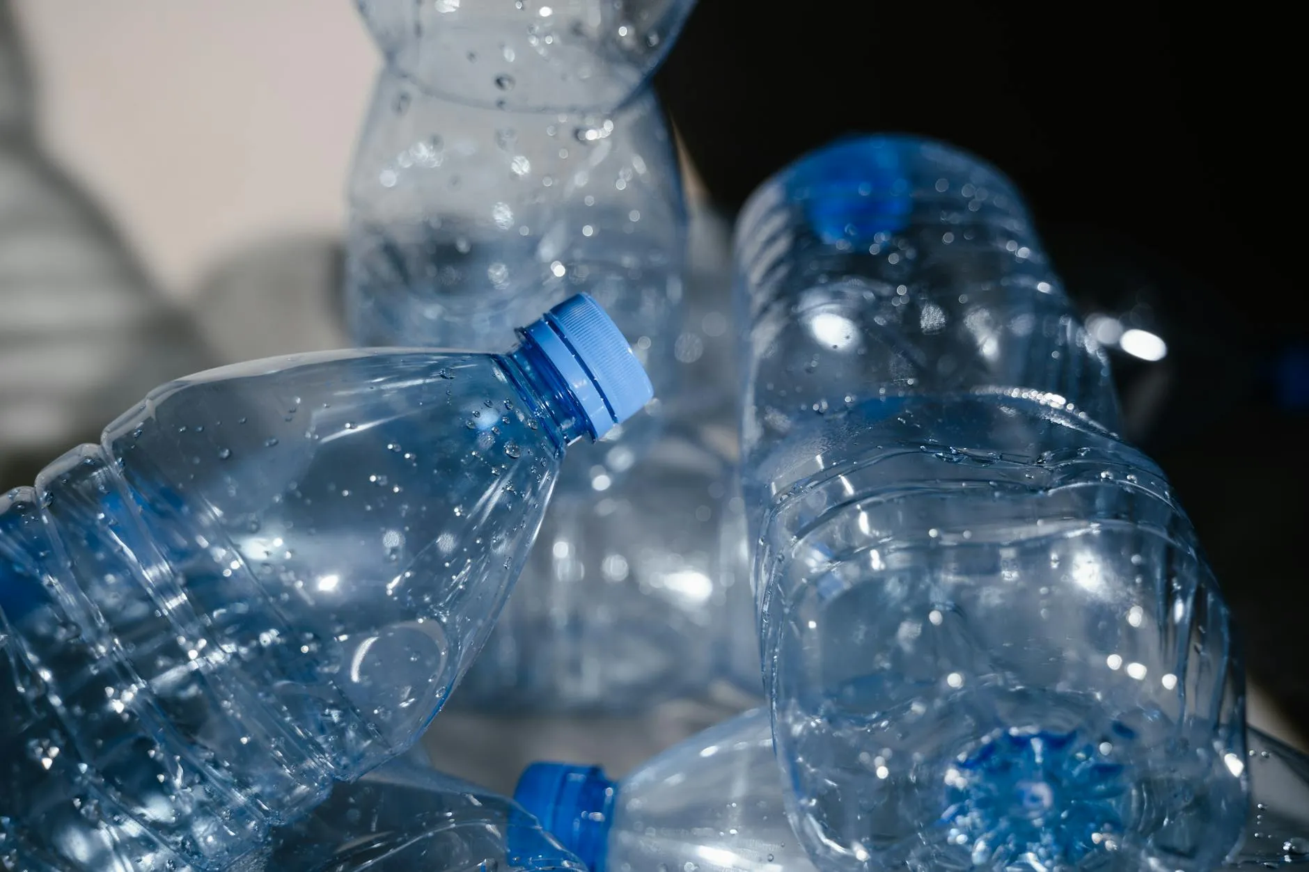 Nærbillede af flere tomme plastflasker med vanddråber, der tydeligt understreger genbrug og affaldssortering. Motivet fremhæver materialet og dets potentiale for genanvendelse.