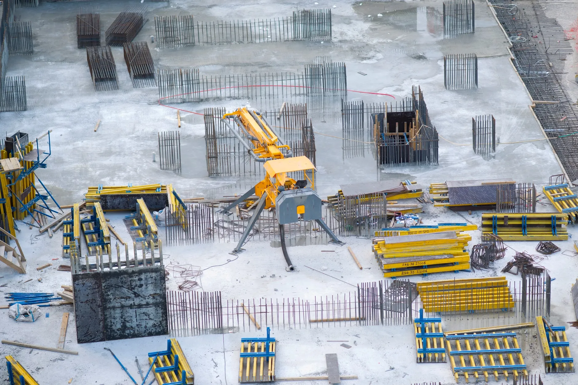Et luftfoto af en travl byggeplads med kraner, bulldozere og materialer. Scenen viser intens byggeaktivitet og igangværende opførelse.