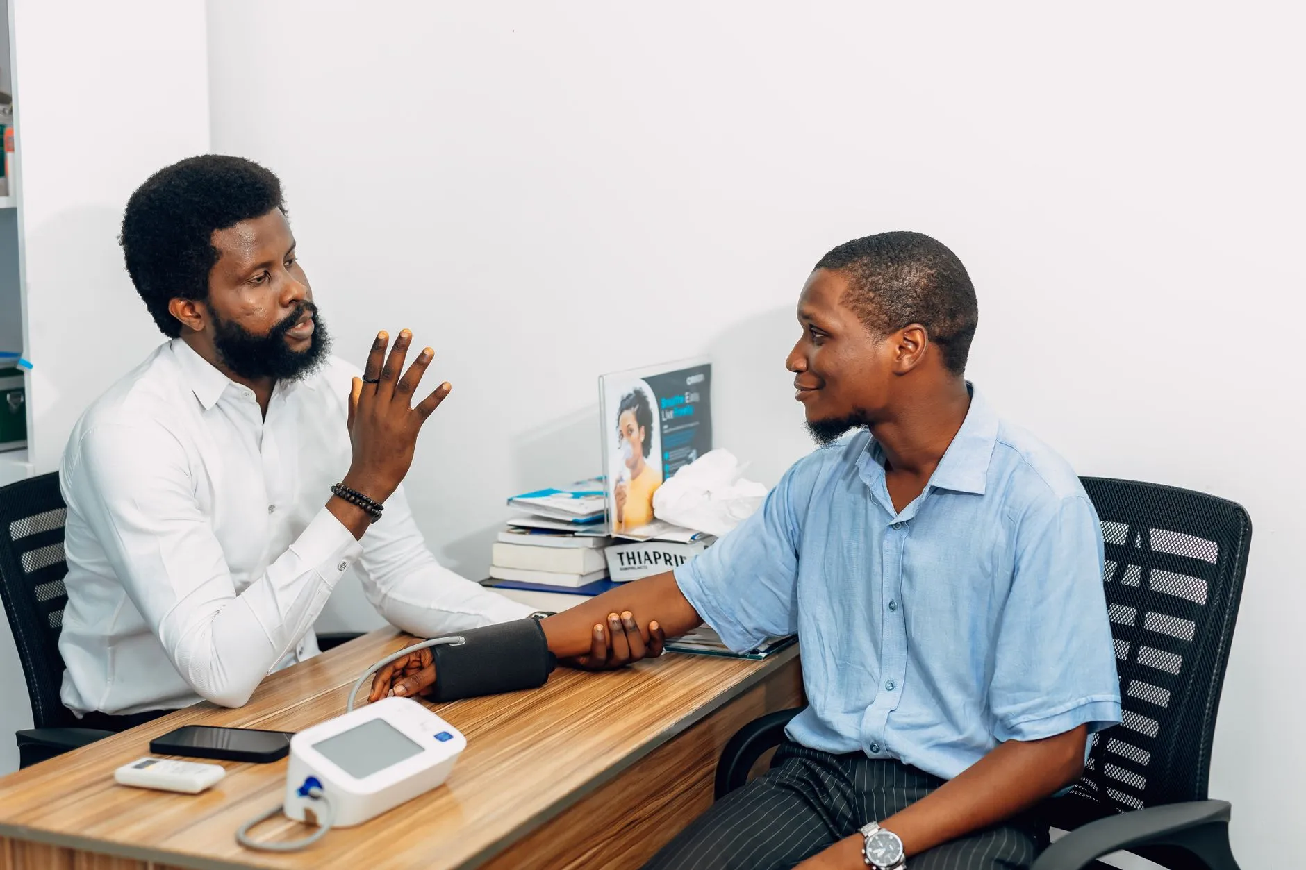 En sundhedsprofessionel foretager en blodtryksmåling under en konsultation. Billedet illustrerer klinisk kontrol og patientomsorg i Lagos, Nigeria.