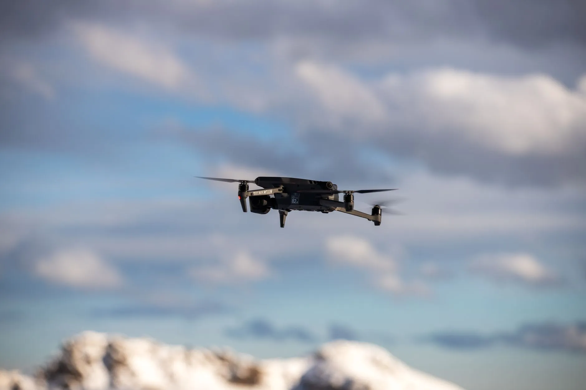 Et fly ses på himlen mod en skyet baggrund, fanget i et dynamisk perspektiv. Billedet understreger bevægelse og luftfartens atmosfære.