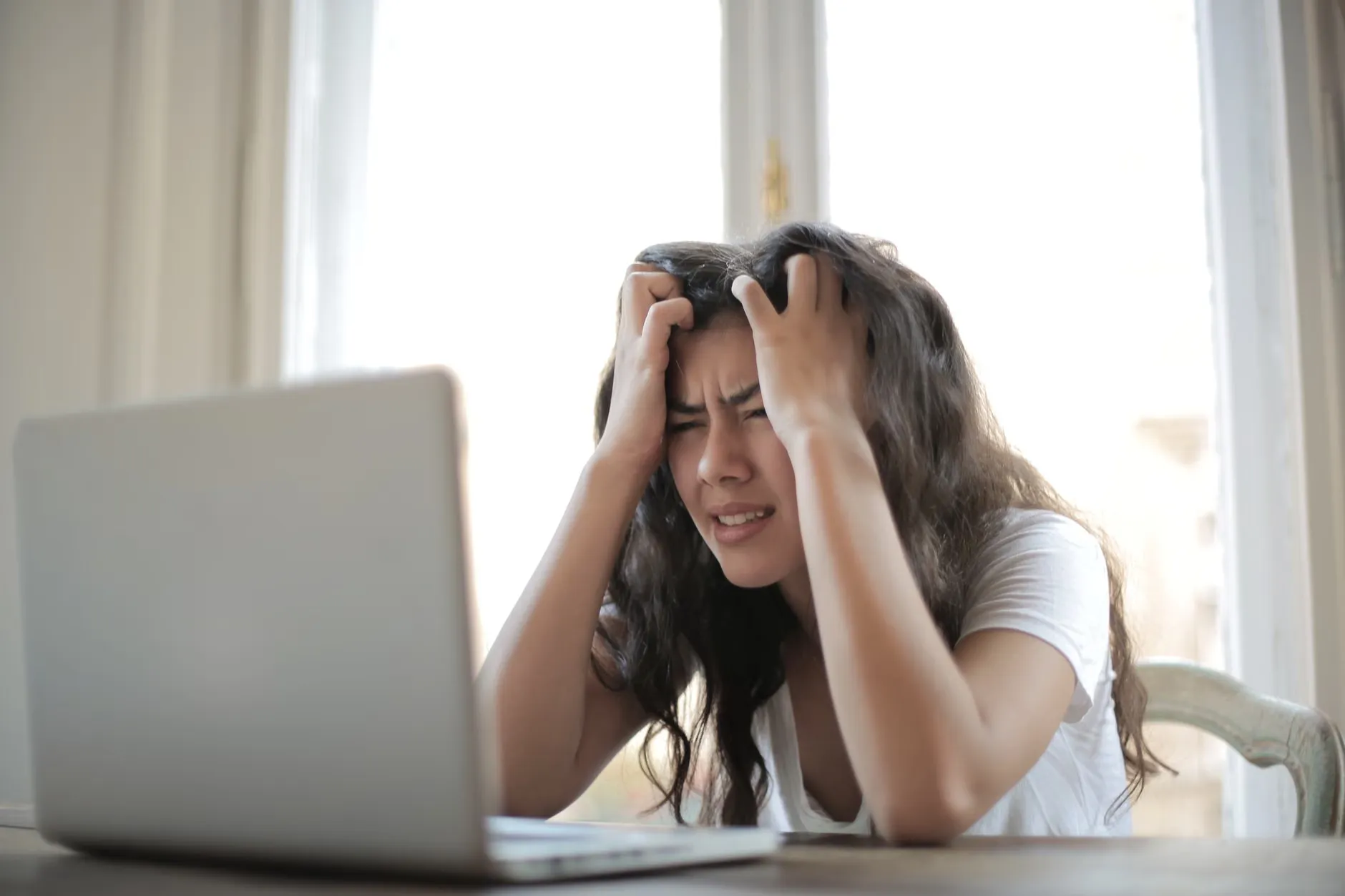 En kvinde oplever frustration under hjemmearbejde på grund af digitale udfordringer.
