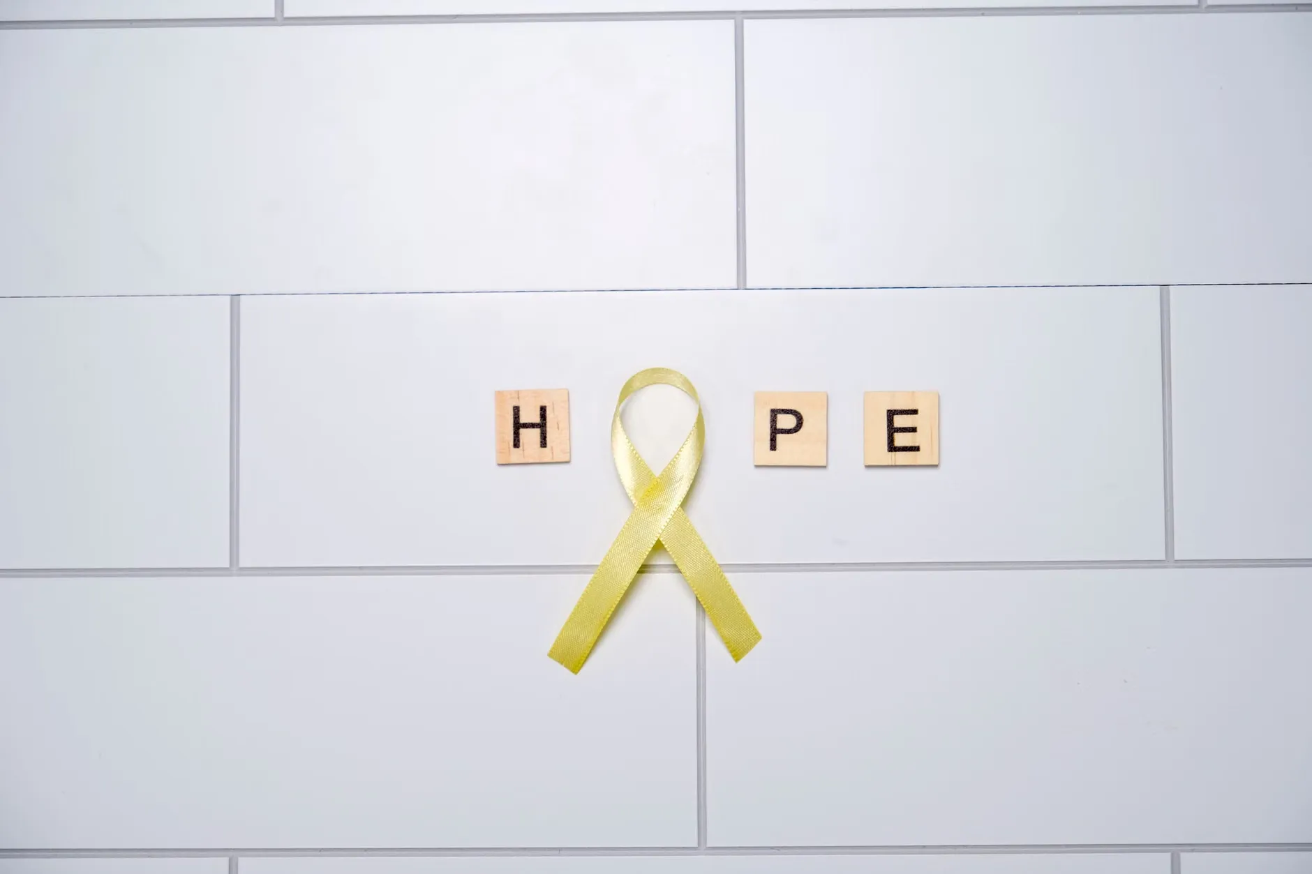 Et billede af håb symboliseret gennem gule bånd, der danner ordet 'hope' på en hvid baggrund.