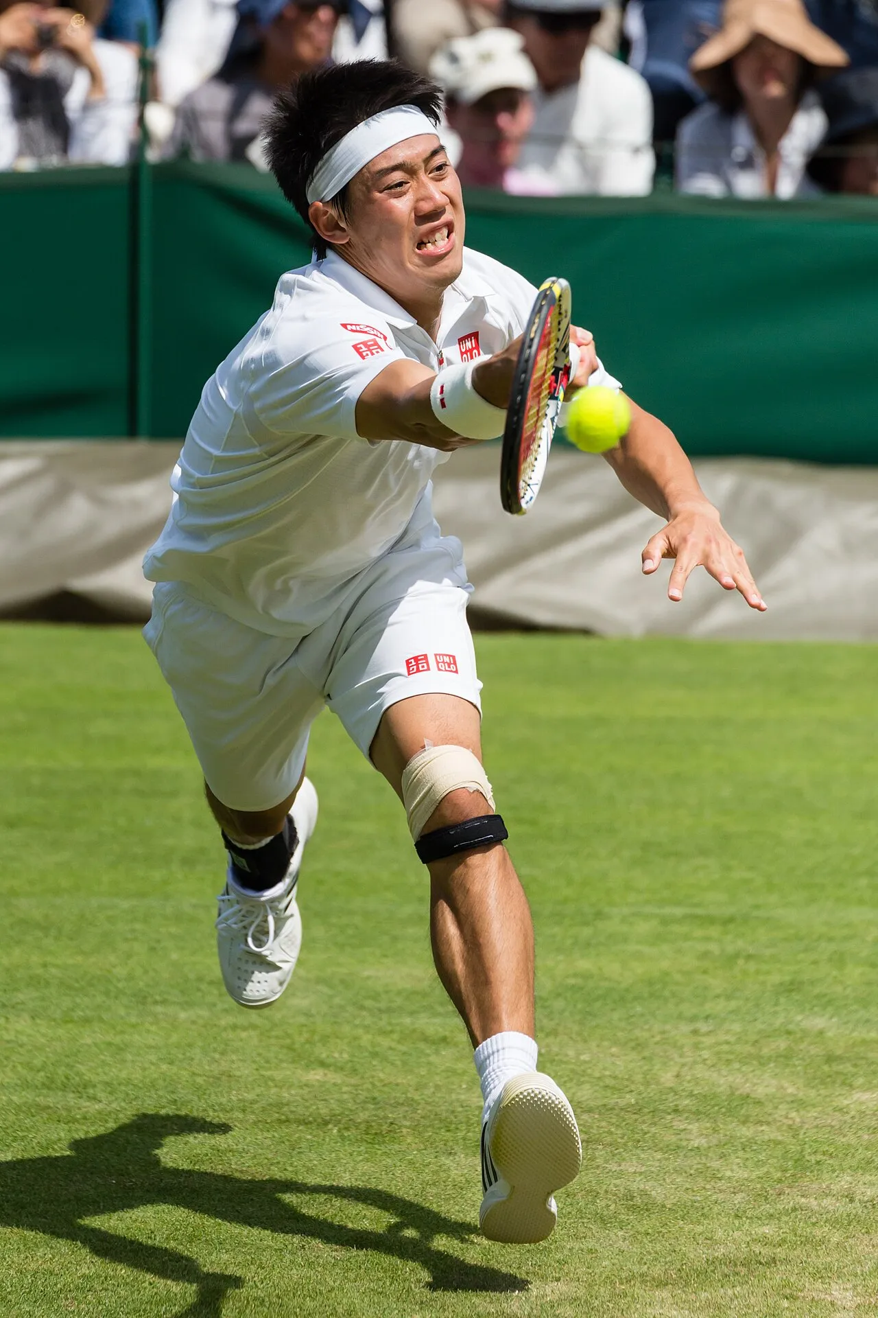 Kei Nishikori er i bevægelse og angriber bolden under sin første runde-kamp ved Wimbledon 2013. Billedet er taget i kampen mod Matthew Ebden.