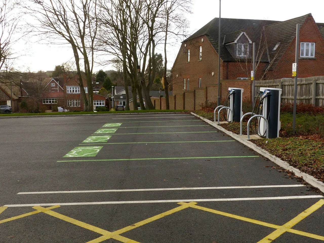Et nærbillede af ladestandere i en offentlig parkeringsplads, der viser infrastrukturen til bæredygtig transport. Fokus er på elbil-ladning som en del af hverdagen.