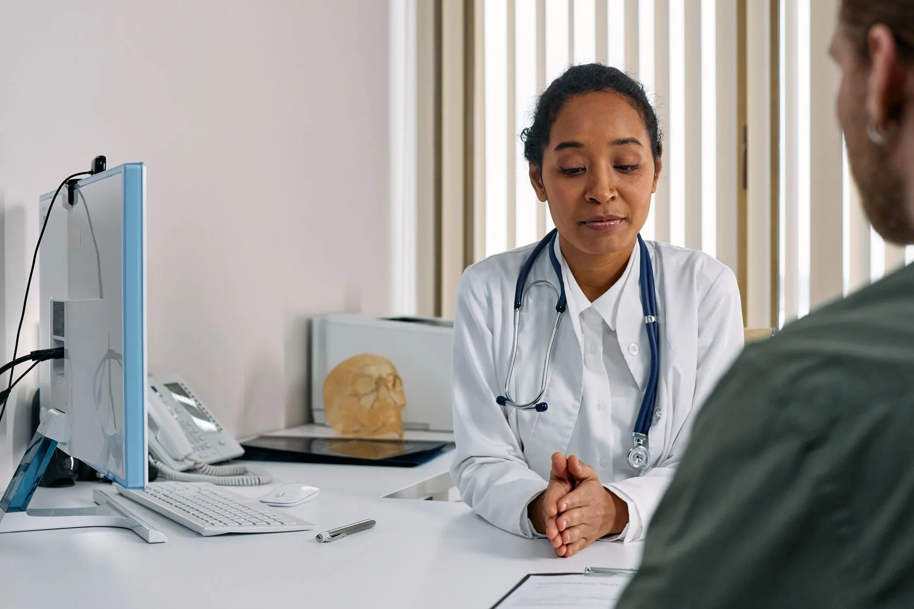 En kvindelig læge sidder og taler med en patient i et moderne behandlingslokale. Scenen udstråler tryghed, omsorg og professionel rådgivning.