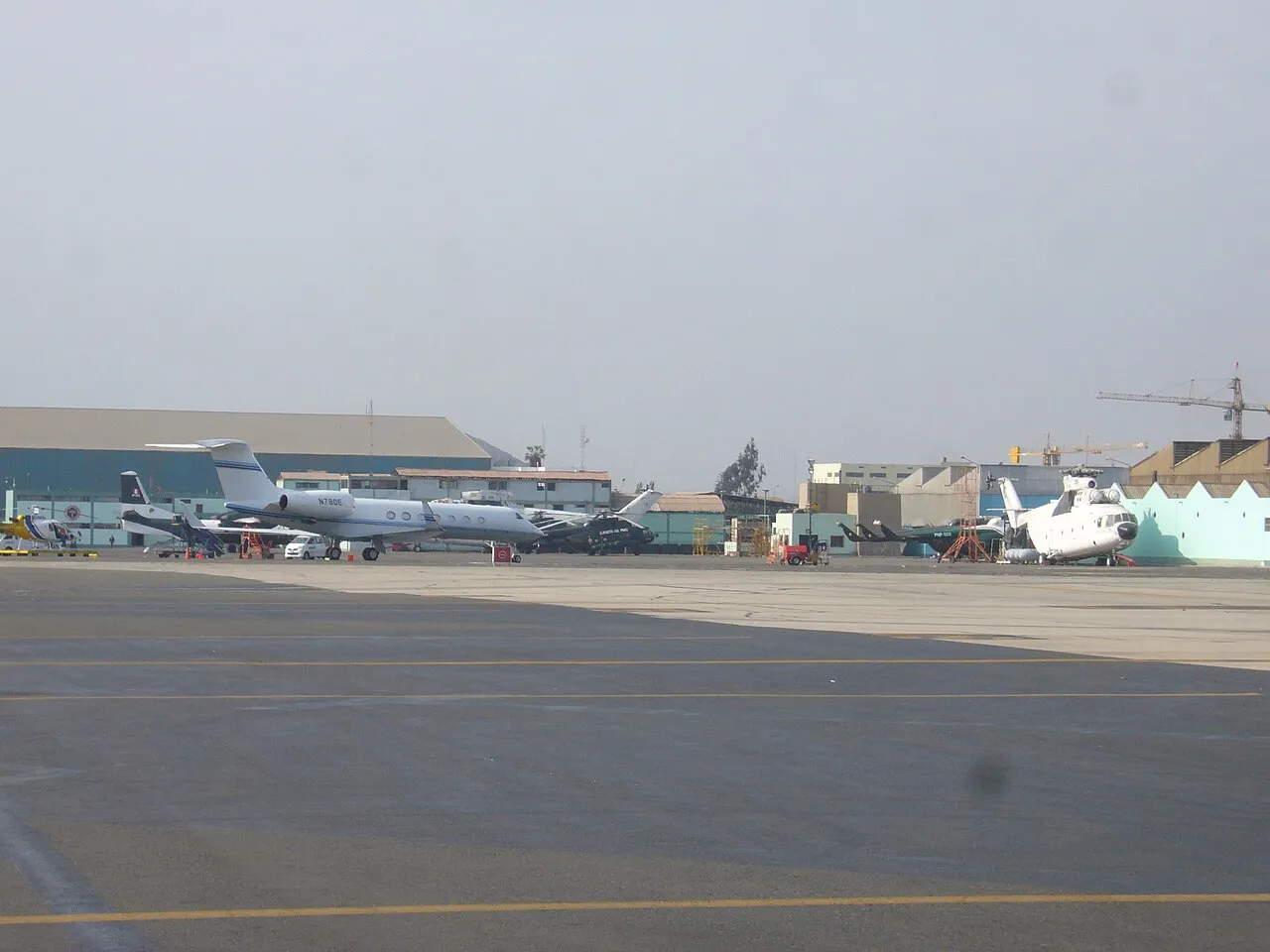 En samling militærfly, herunder Mi-26, Mi-8 og An-32, på Jorge Chávez International Airport i Lima. Billedet viser flere fly parkeret på flyvepladsen.