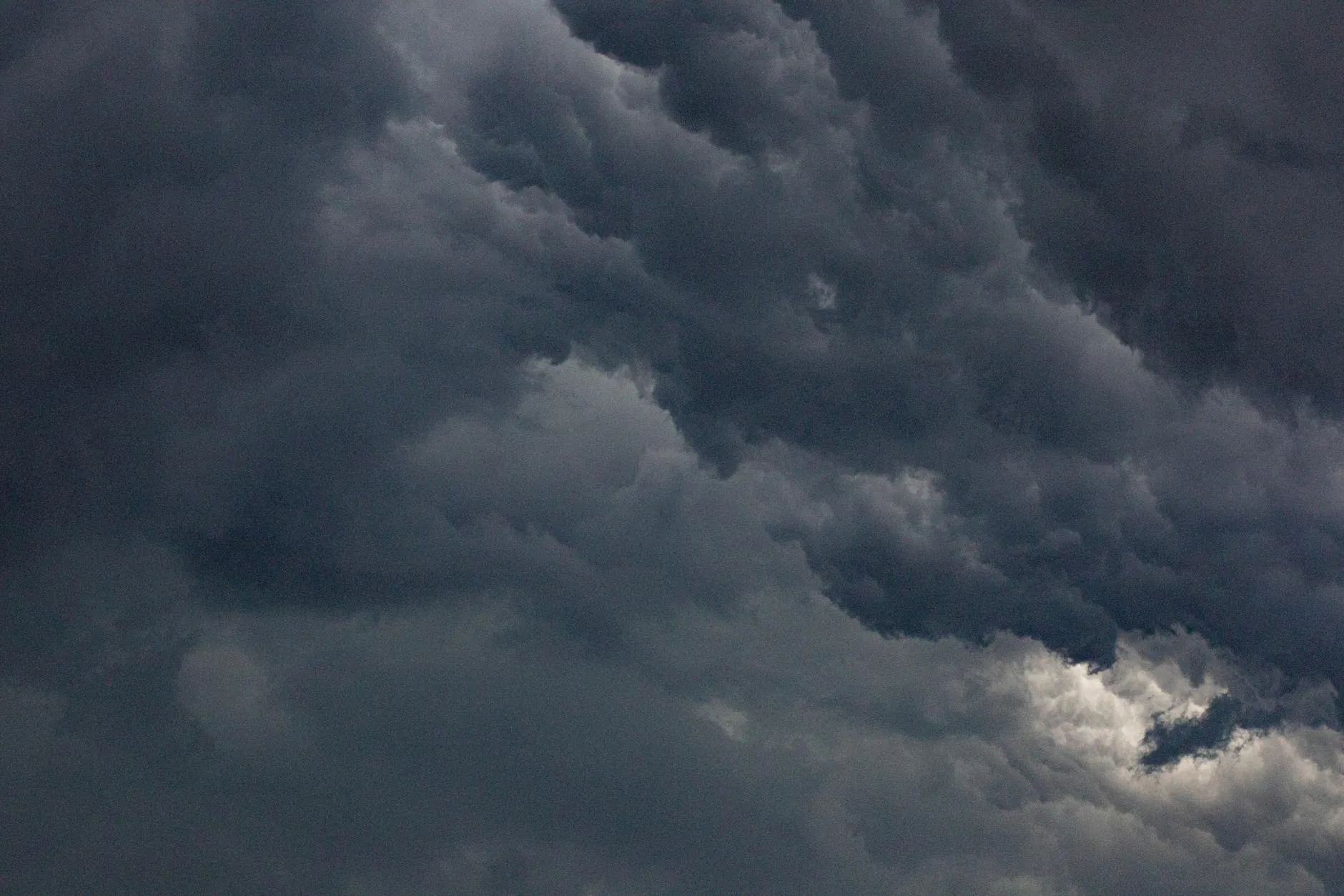 En dramatisk himmel fyldt med tætte, mørke skyer skaber en intens og uvejrsmættet stemning. Billedet understreger kontrasten mellem lys og skygger i naturen.