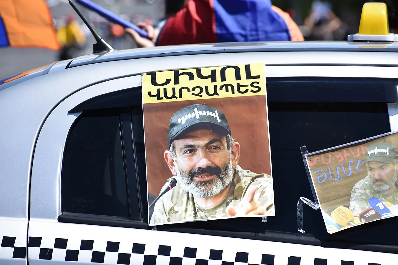 En plakat med Nikol Pashinyan ses på en bil på Komitas Avenue i Yerevan. Billedet fanger et politisk motiv i bybilledet.