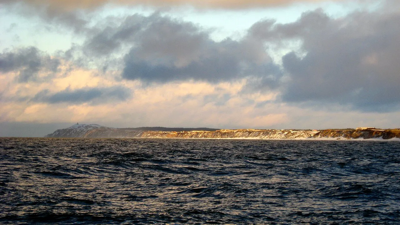 En orange redningsbåd bliver sænket ned i havet fra et skib. Scenen illustrerer sikkerhed og beredskab til søs.