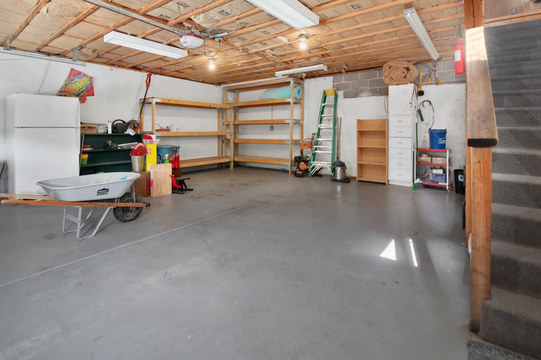 En rummelig garage med hylder til opbevaring, værktøj og en trillebør. Billedet illustrerer praktisk organisering og funktionelle hjemmeløsninger.