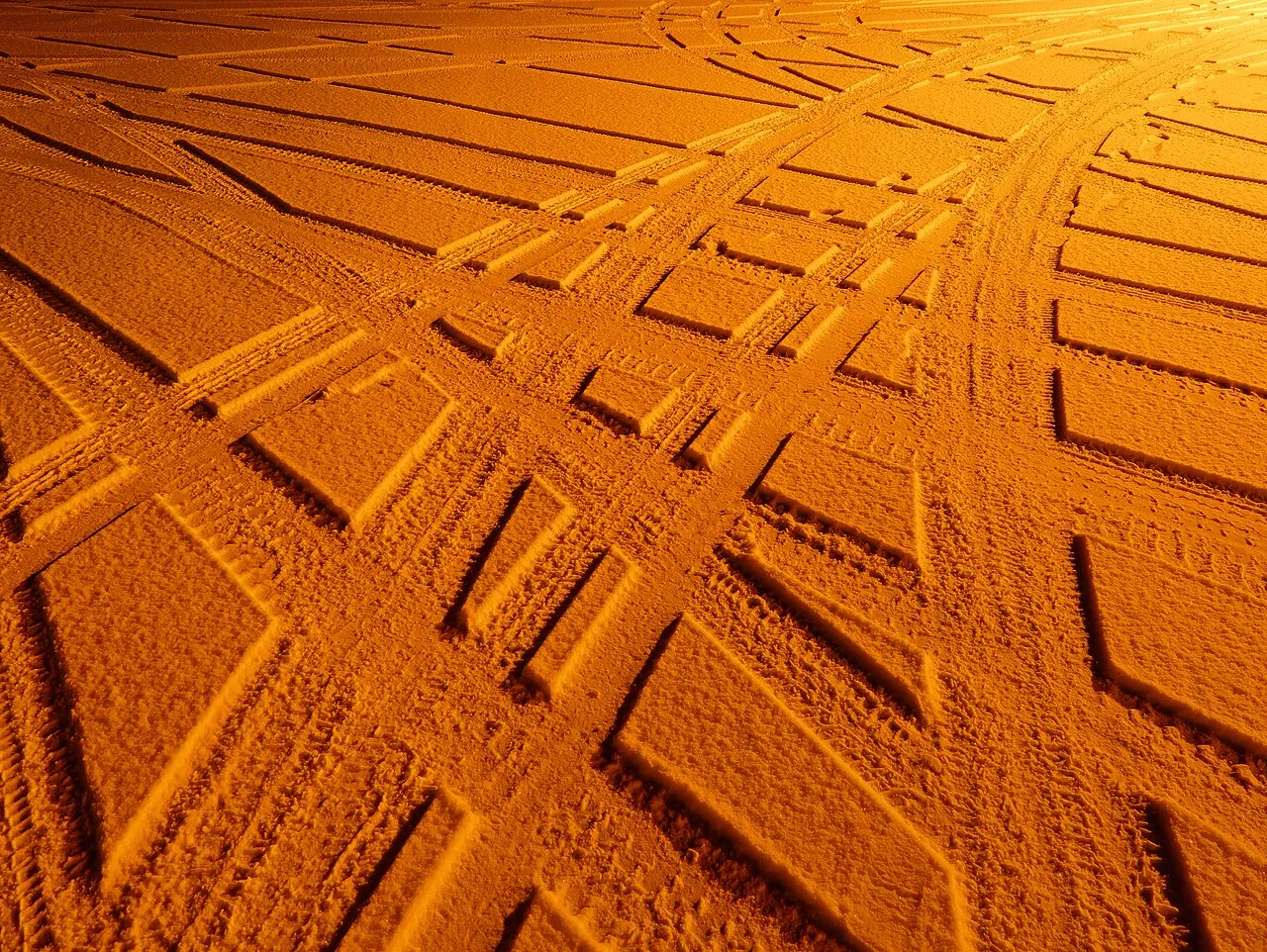 Car tire tracks i sneen under en sodium lys, i en parkeringsplads i Gåseberg, Lysekil Kommune, Sverige.