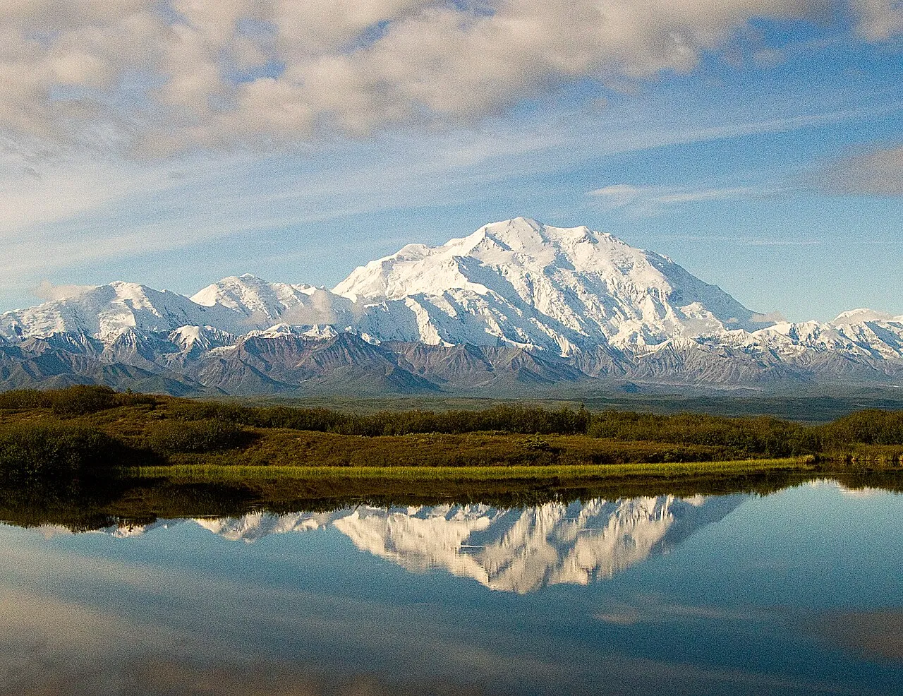 Wonder Lake med Denali i baggrunden, hvor landskabet spejler sig i det stille vand. Billedet viser en rolig naturscene fra Denali National Park.