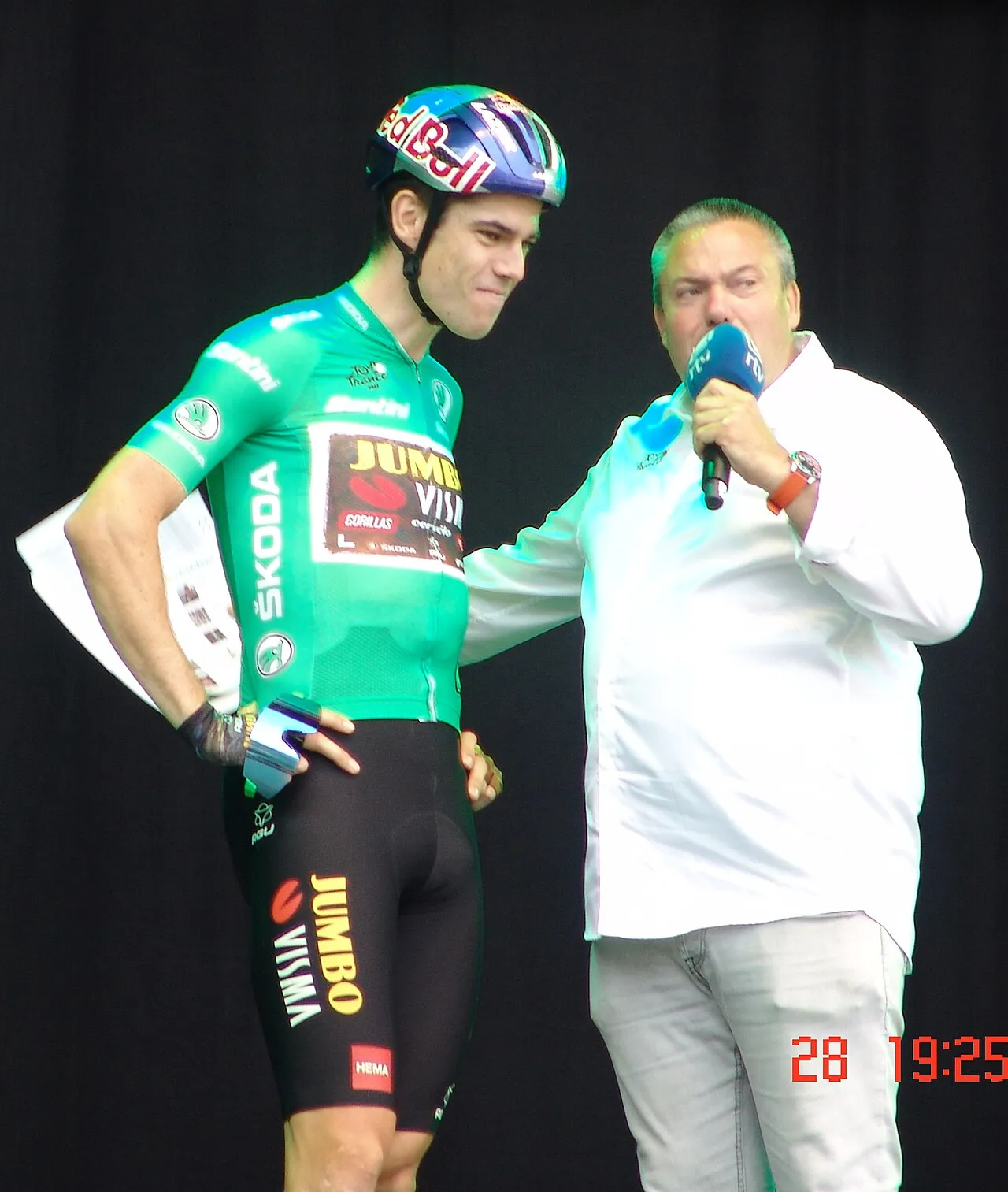 Wout van Aert ses på scenen i sin grønne Tour de France-trøje under Herentals-arrangementet i 2022. Billedet fanger ham i et markant øjeblik i cykelsportens farver.
