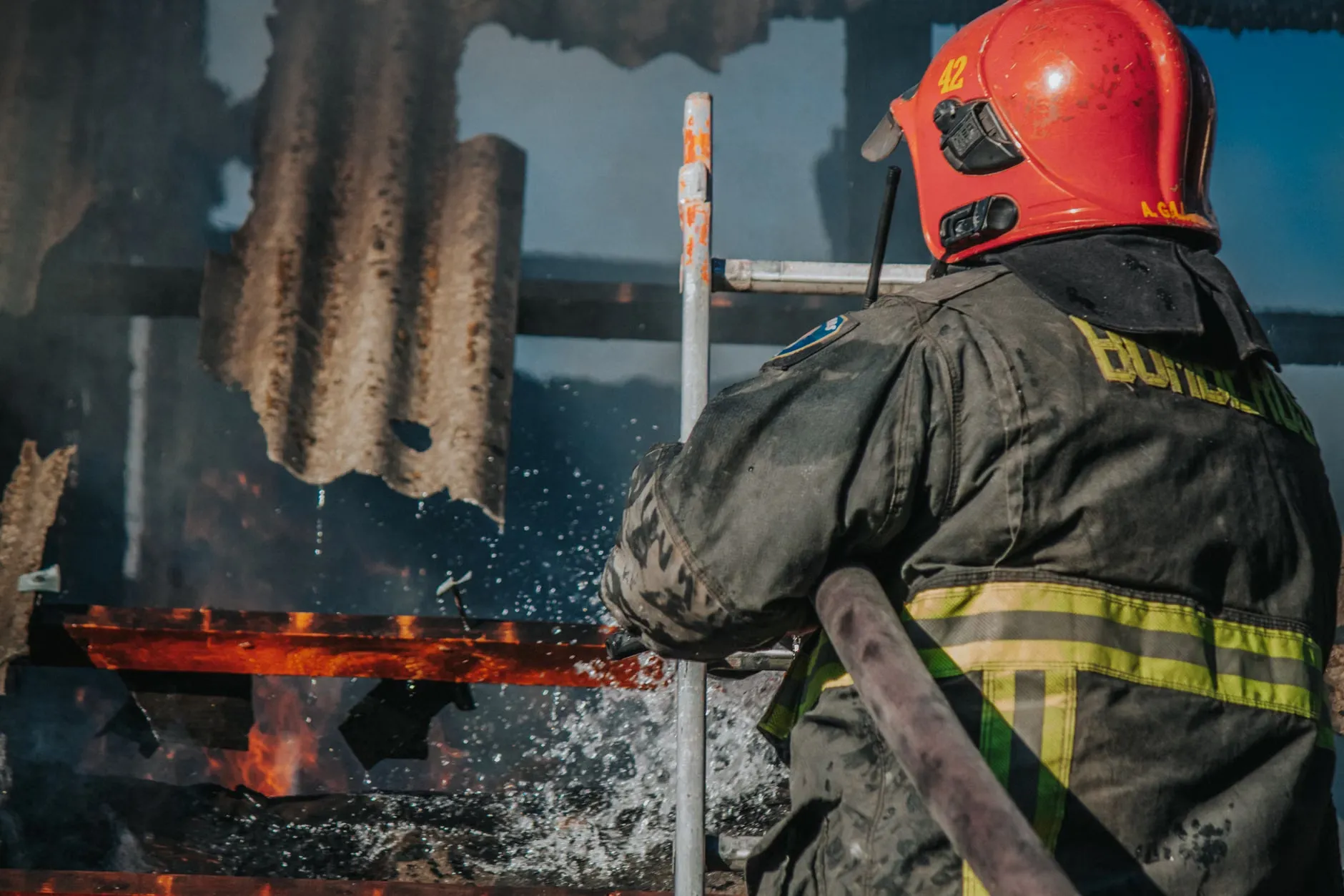 En dedikeret brandmand bekæmper flammer i en brændende bygning. Scenen viser brandmandens mod og professionelle indsats.