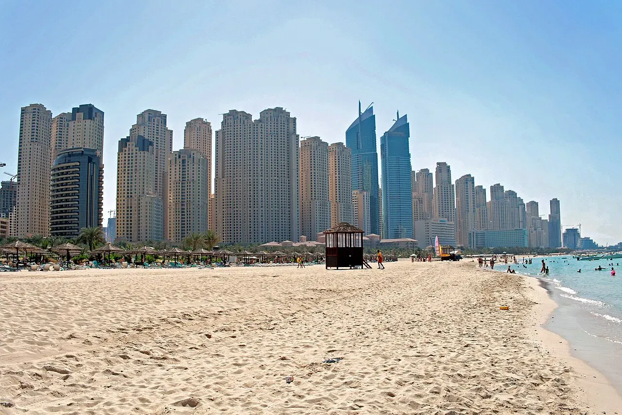 Det ikoniske skyline af Dubai Marina reflekterer i vandet ved Jumeirah Beach, og viser byens arkitektoniske storhed.