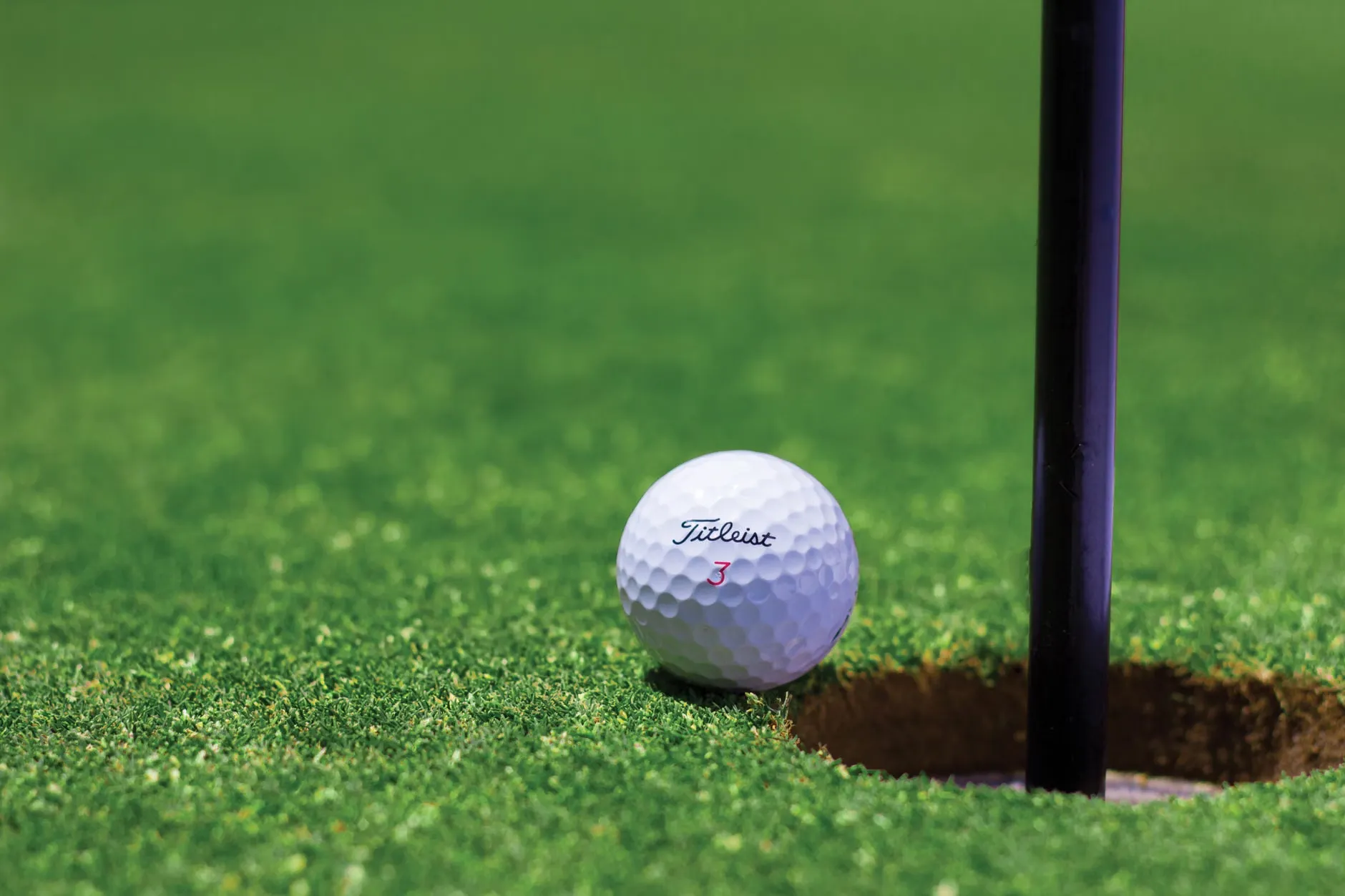 Et nærbillede af en golfbold nær et hul på en farverig golfbane, der fanger øjeblikket af næsten at lykkes.