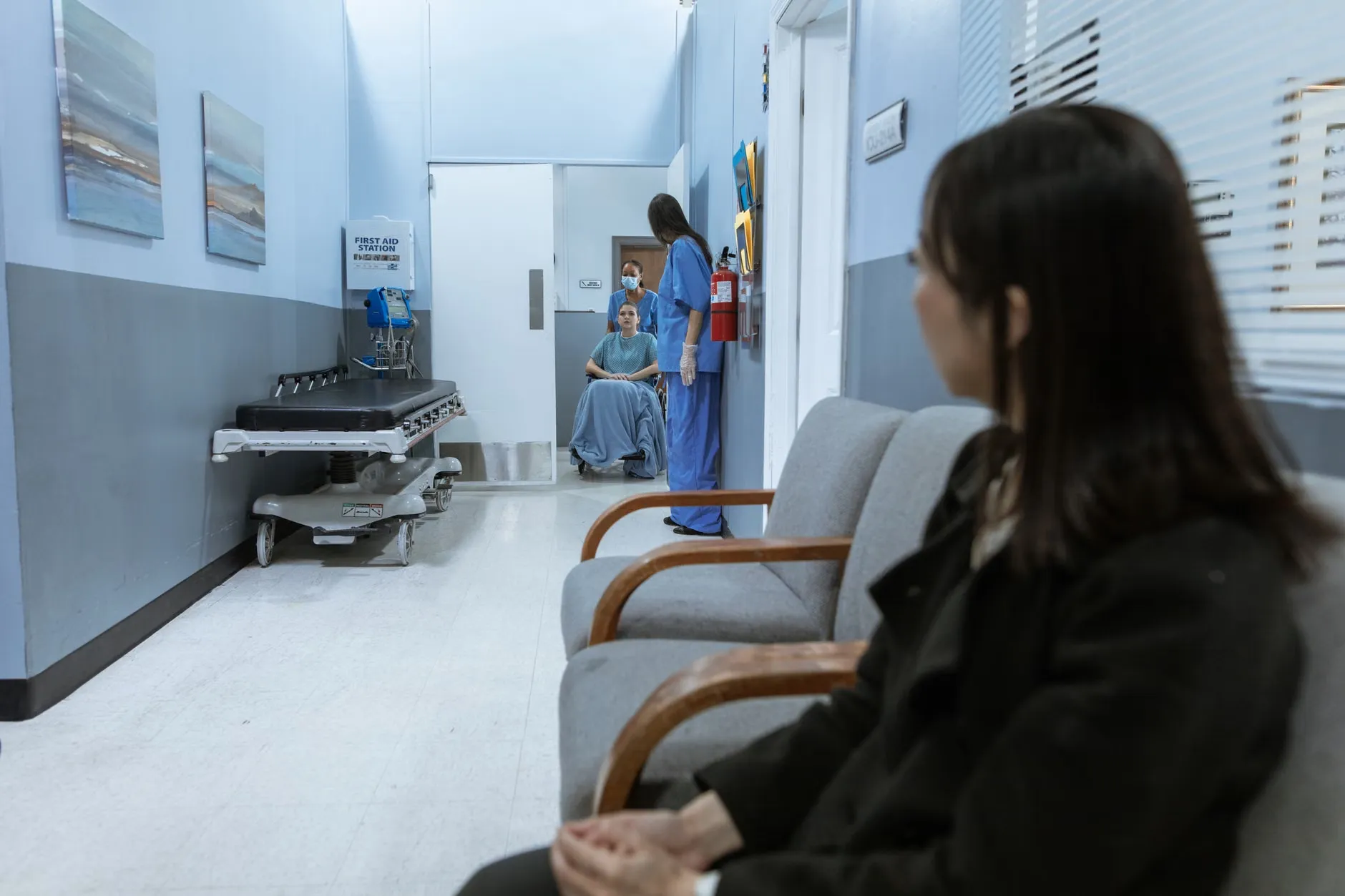 En hospitalgang med patienter og medicinsk personale i bevægelse. Scenen viser et typisk sundhedsmiljø og understreger fokus på behandling og omsorg.