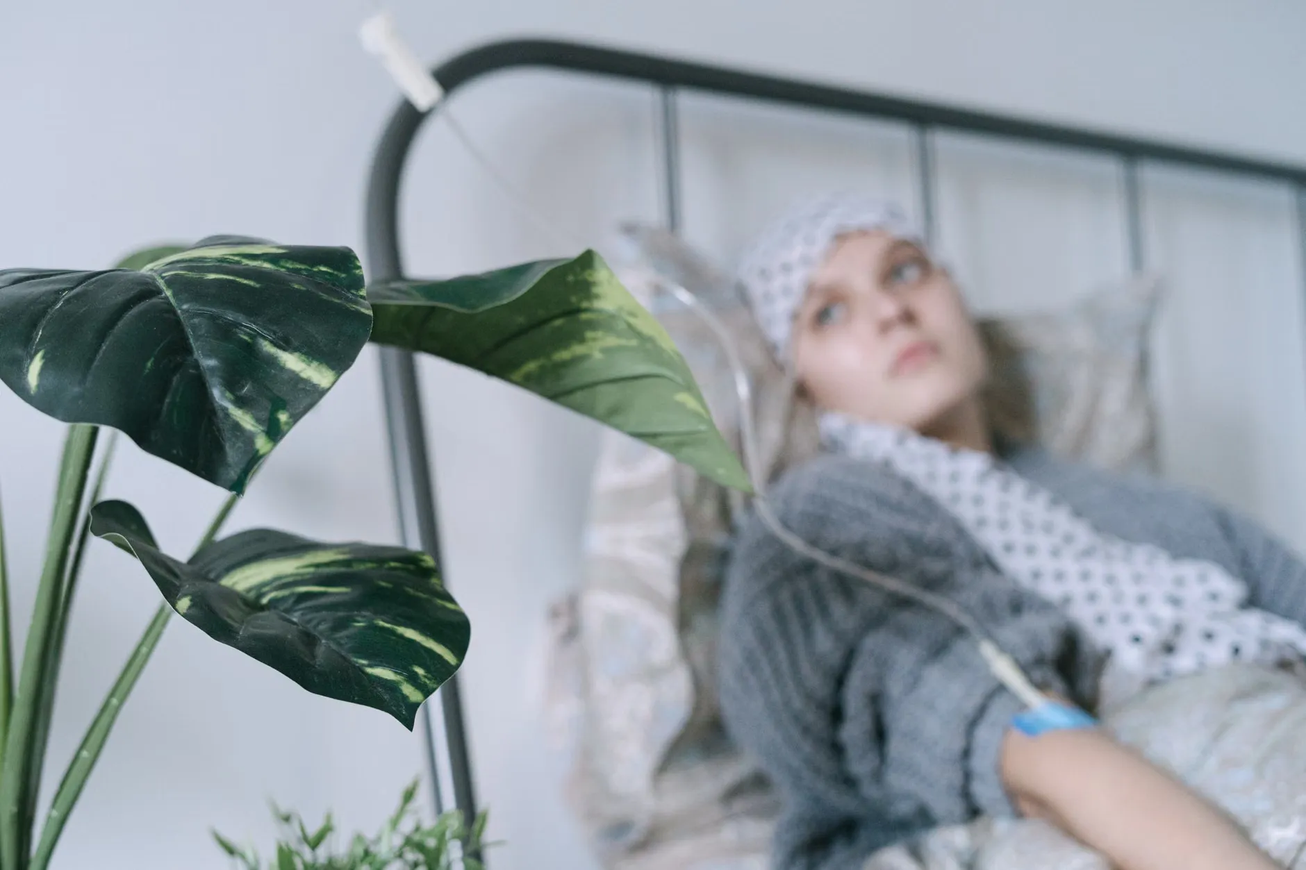En kræftpatient ligger på en hospitalsseng med et IV-drop, mens der udstråles håb og bedring. Stemningen understøtter temaer om behandling og recovery.