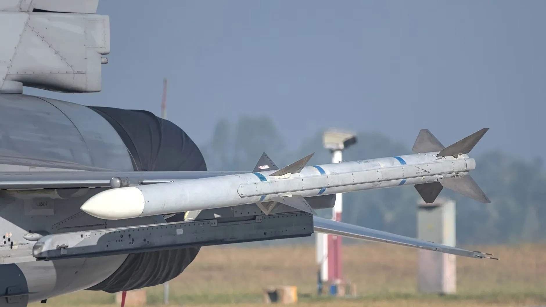 Et tæt billede af et missil monteret på en militær flyvemaskines vinge under en flyshow i Bengaluru, Indien. Billedet viser detaljerne af missilet og flyets metalstruktur.