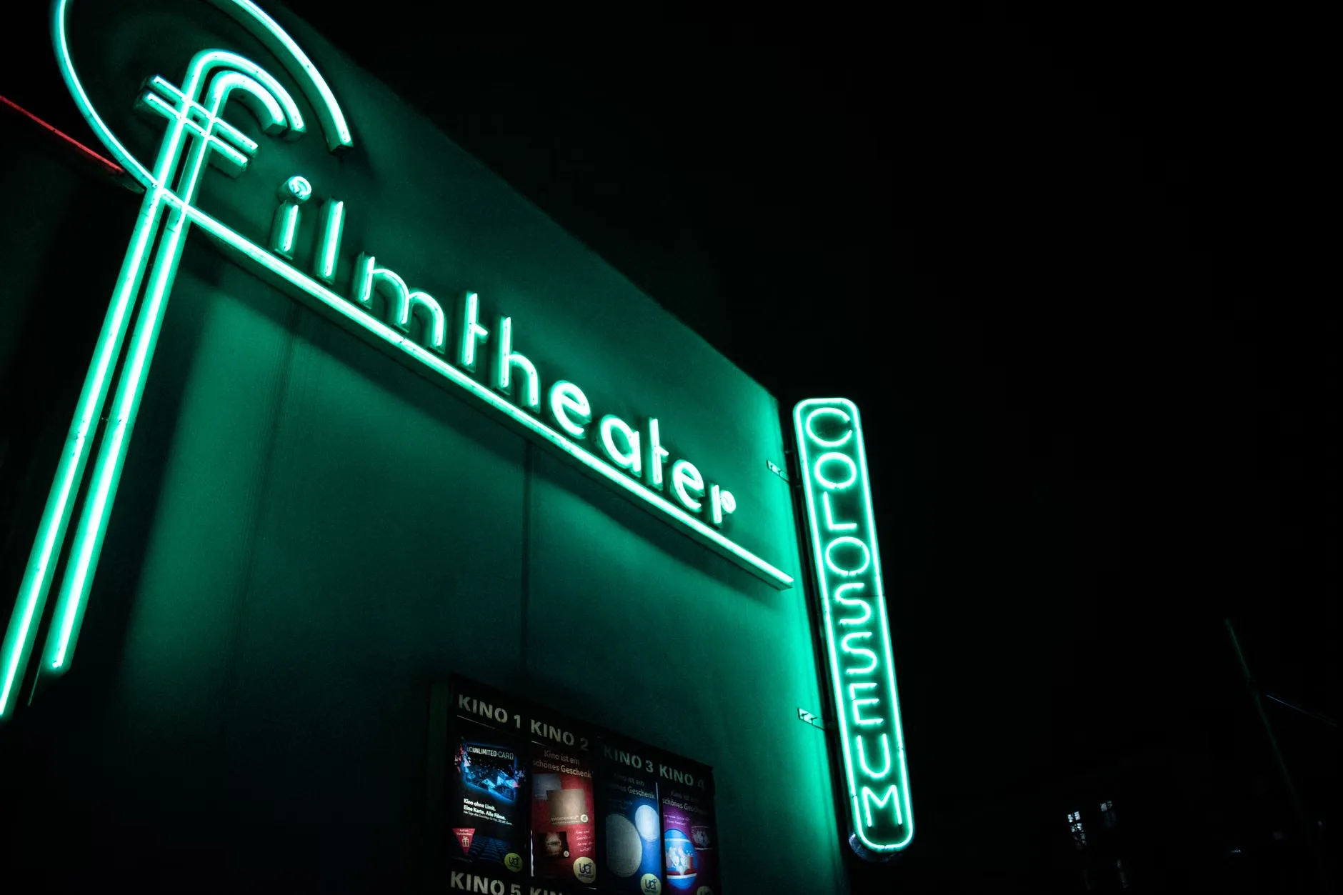 Et farverigt neon skilt for en biograf, der lyser om natten.