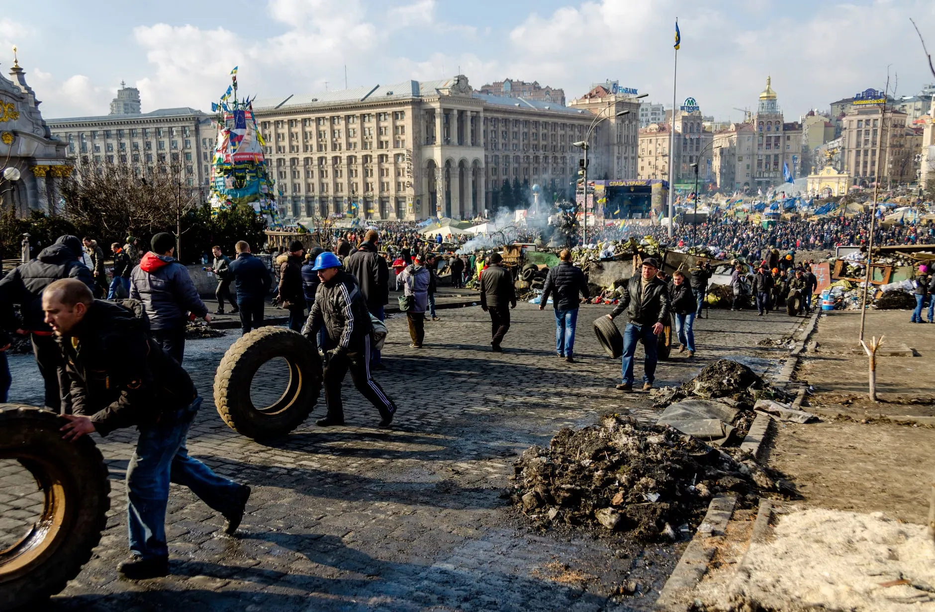En stor menneskemængde samlet på Uafhængighedspladsen i Kyiv, Ukraine, under en protest. Billedet viser en livlig og farverig scene med mange mennesker.