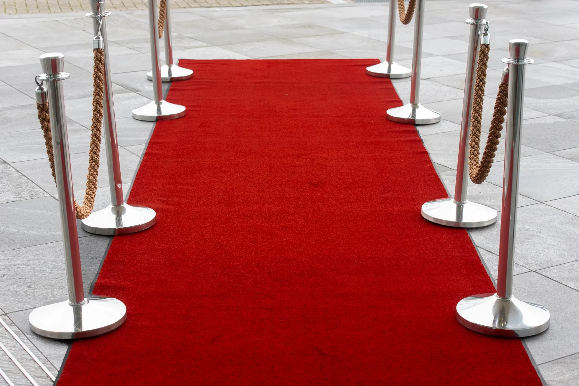 En rød løber med stanchions på en fliset udendørs overflade, perfekt til events.