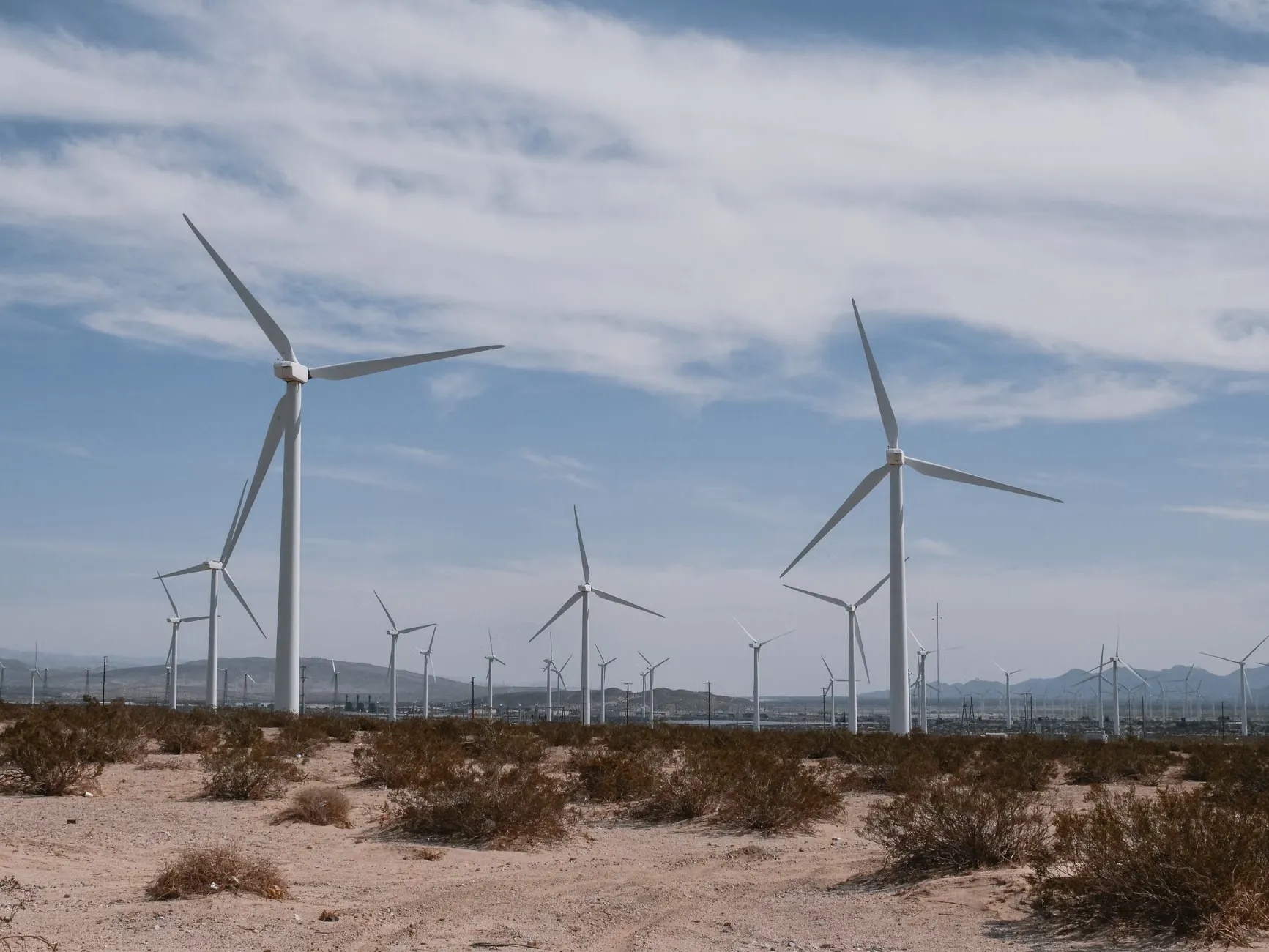 A scenic view of wind turbines in a desert, symbolizing clean, renewable energy technology. Billedet viser vindmøller i en ørken, som symboliserer ren og vedvarende energi.
